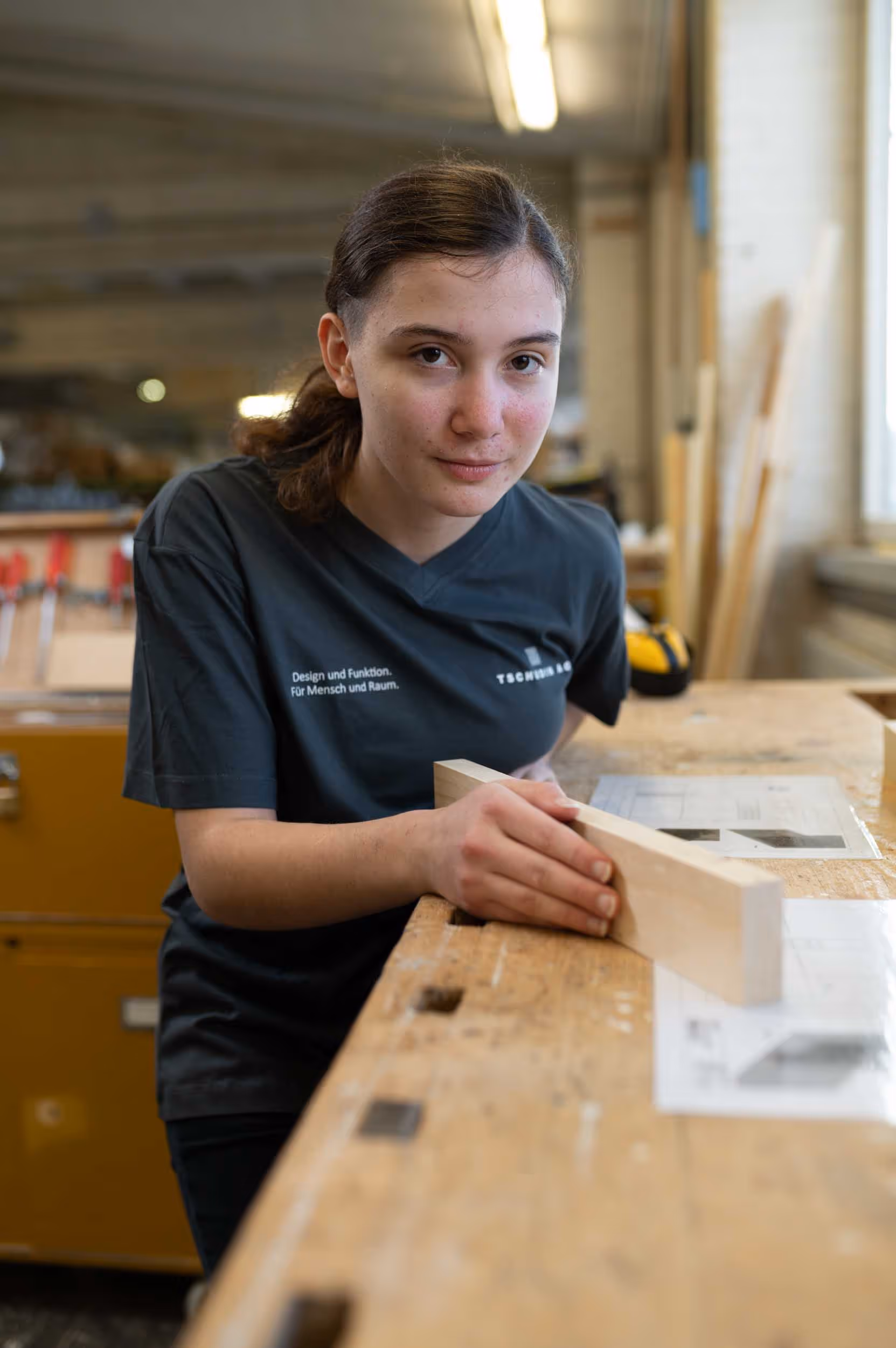 A young woman in a black T-shirt is working on a project.