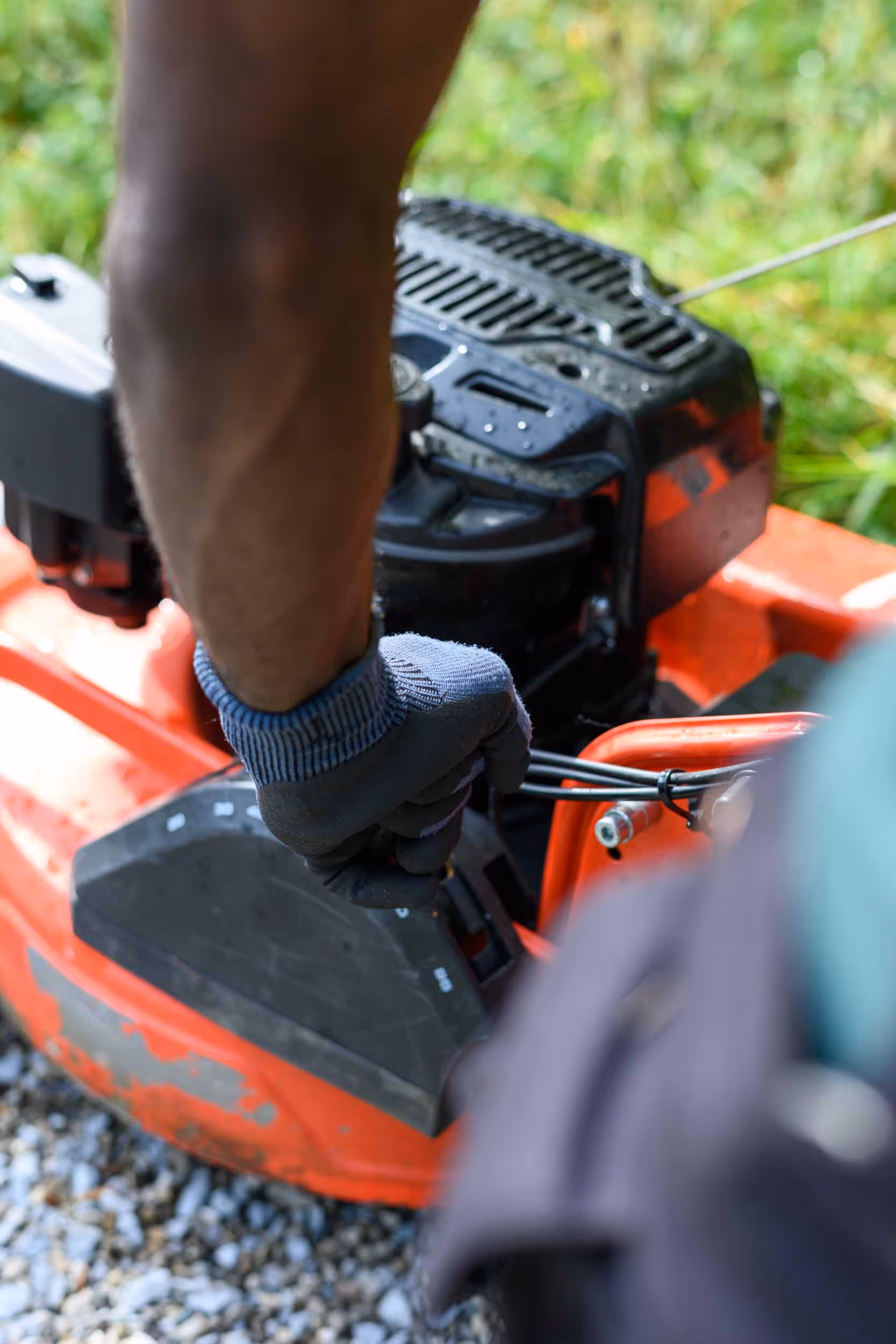 A man works on a red, motorized lawn mower.