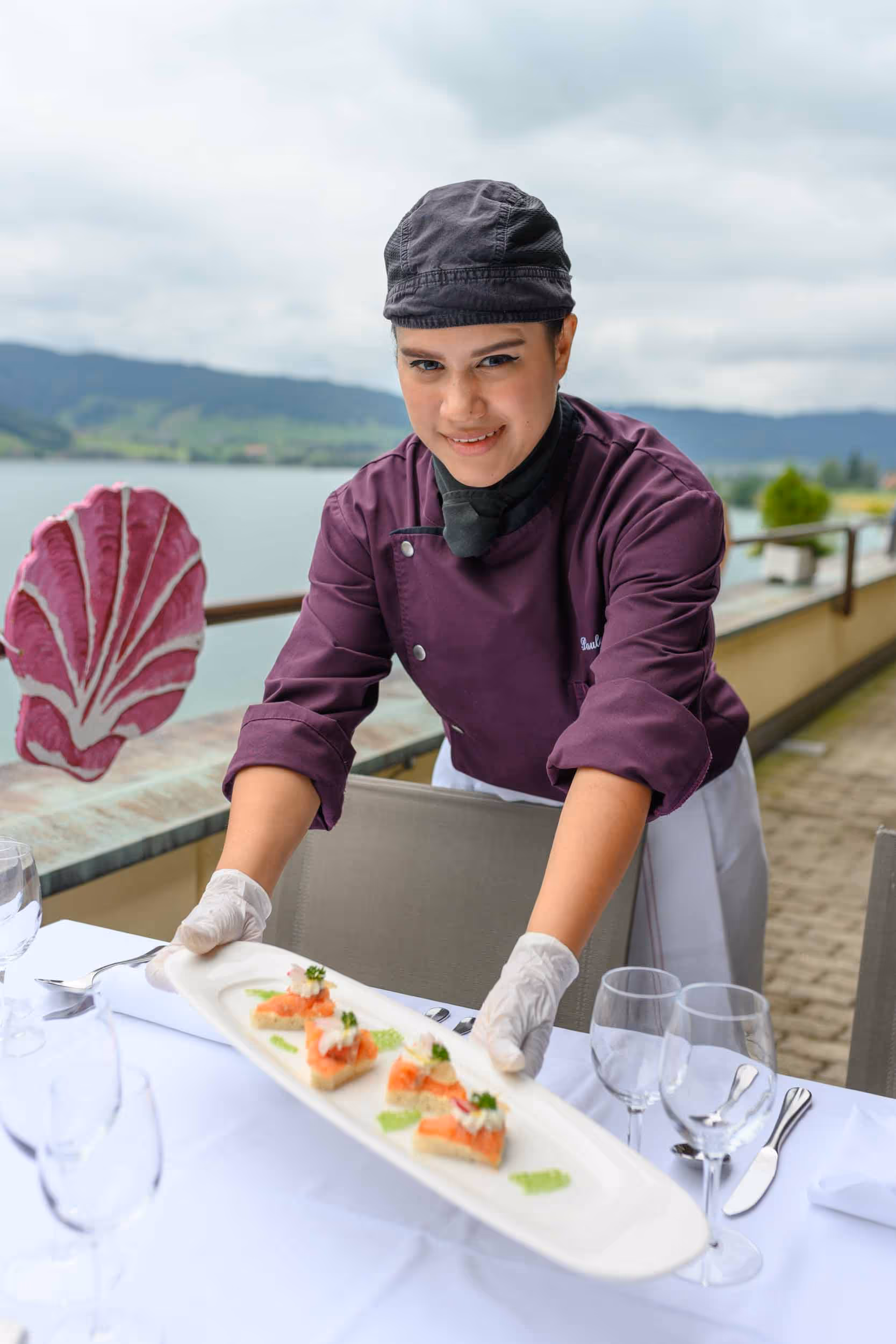 A woman in a purple shirt serves food on a plate.
