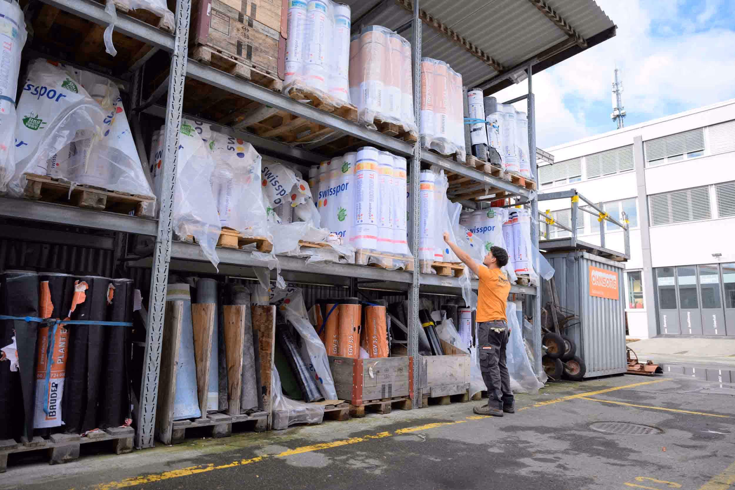 A man stands in front of a large pile of plastic tarpaulins.