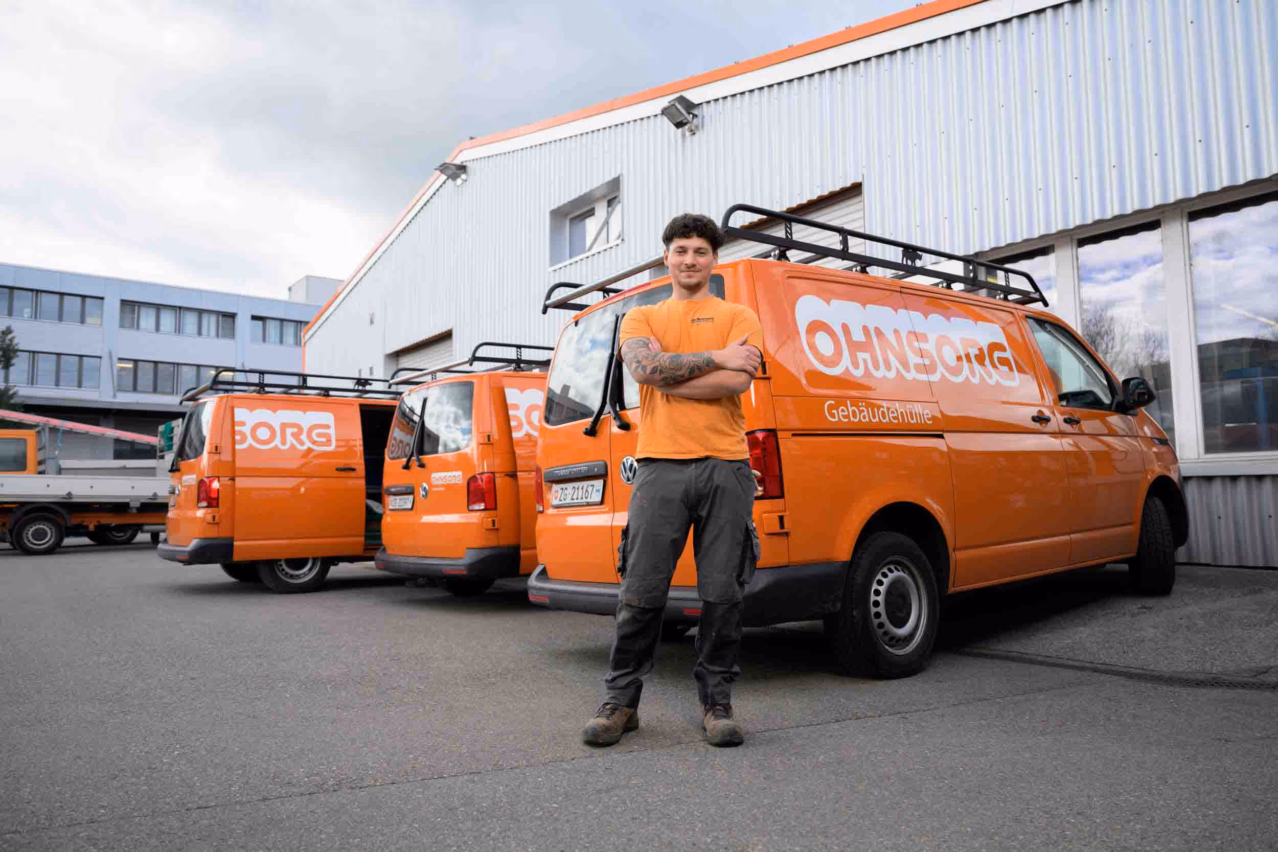 A man stands in front of a row of orange vans.