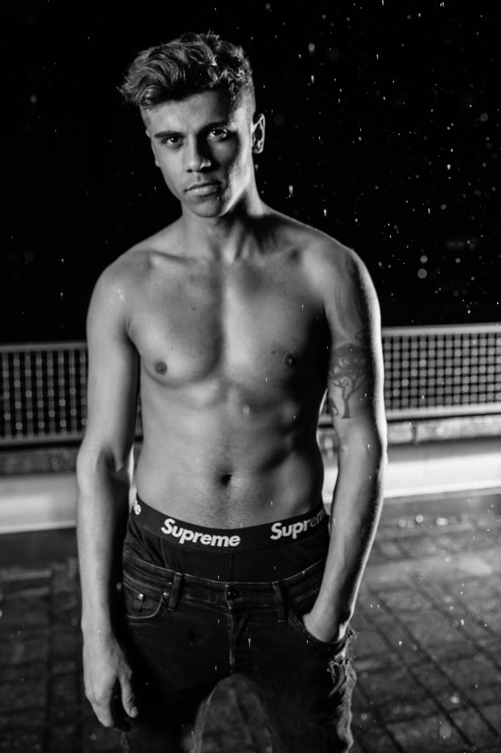 A topless man on a roof in black and white.