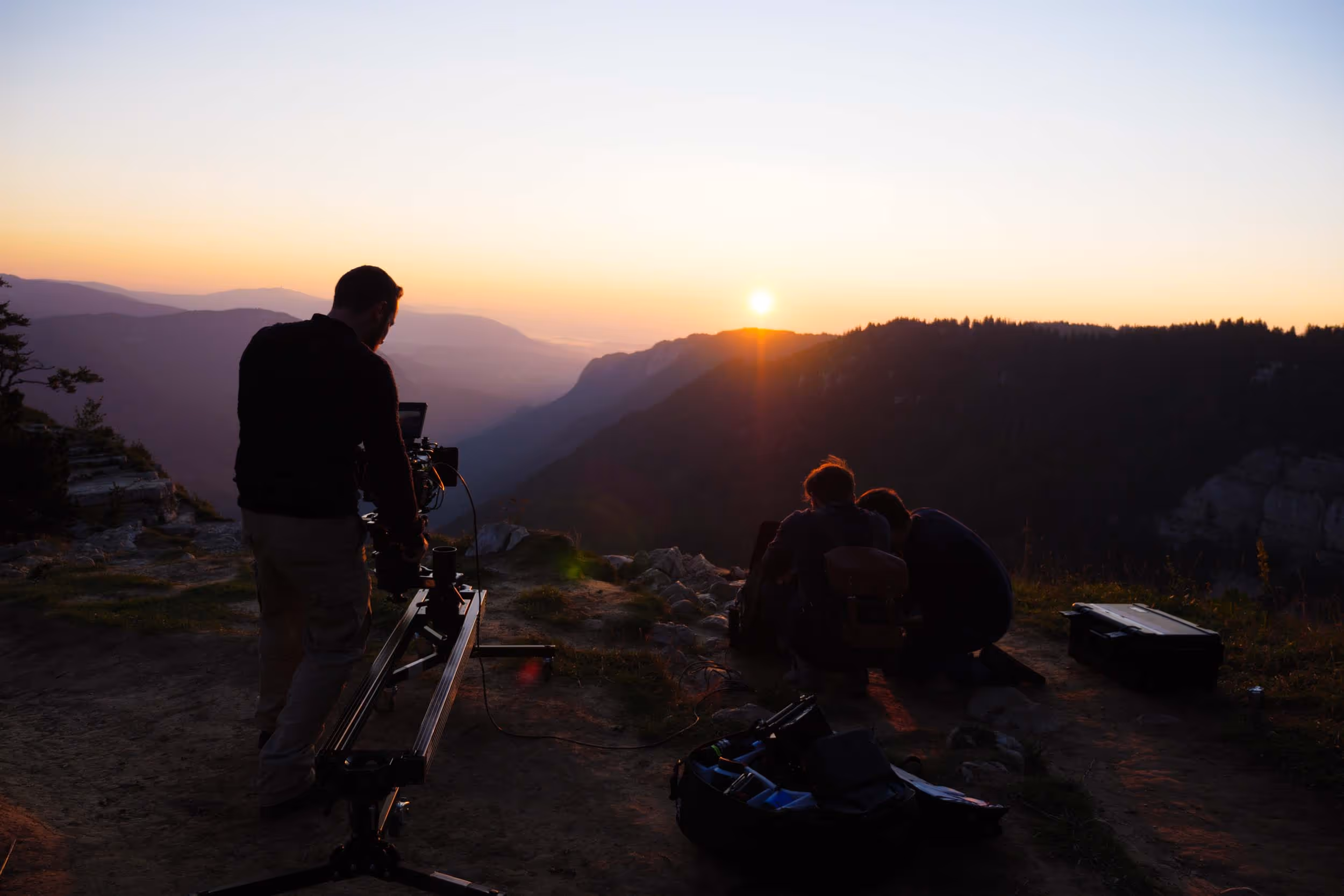 Pascal Wasinger stands on a hill with a camera and a bag of equipment.
