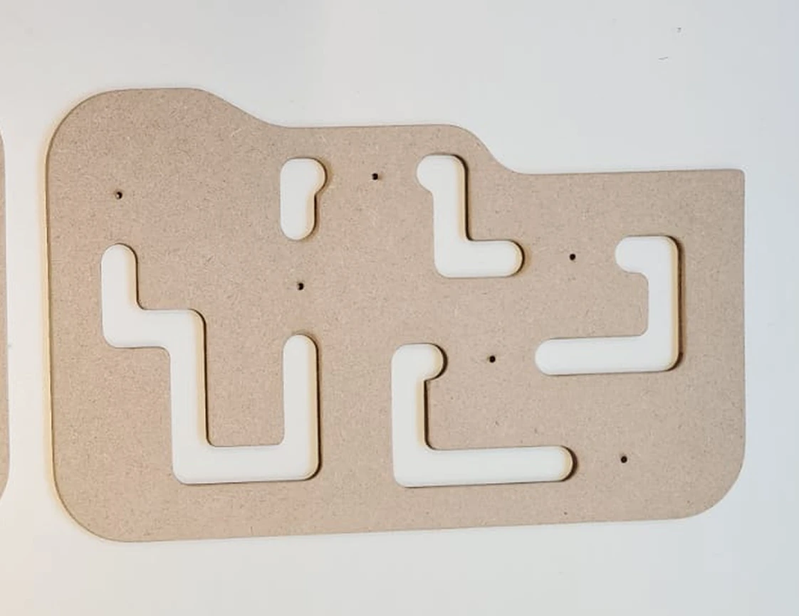 Light brown wooden panel with multiple white L shaped grooves cut into it