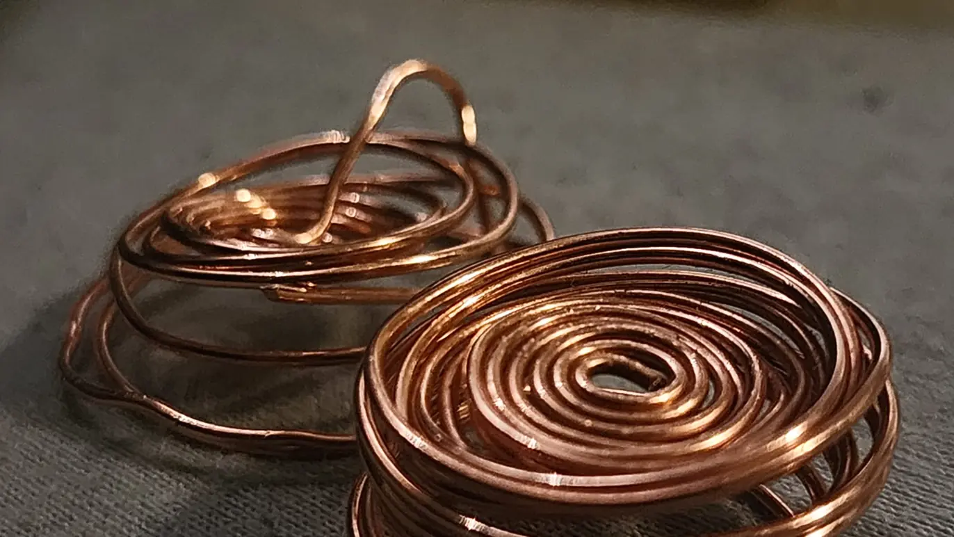 Two copper wire coils on a textured gray surface