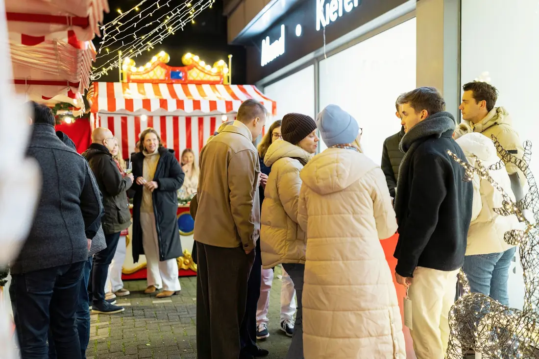 Gäste im Gespräch vor einer rot-weiß gestreiften Marktbude