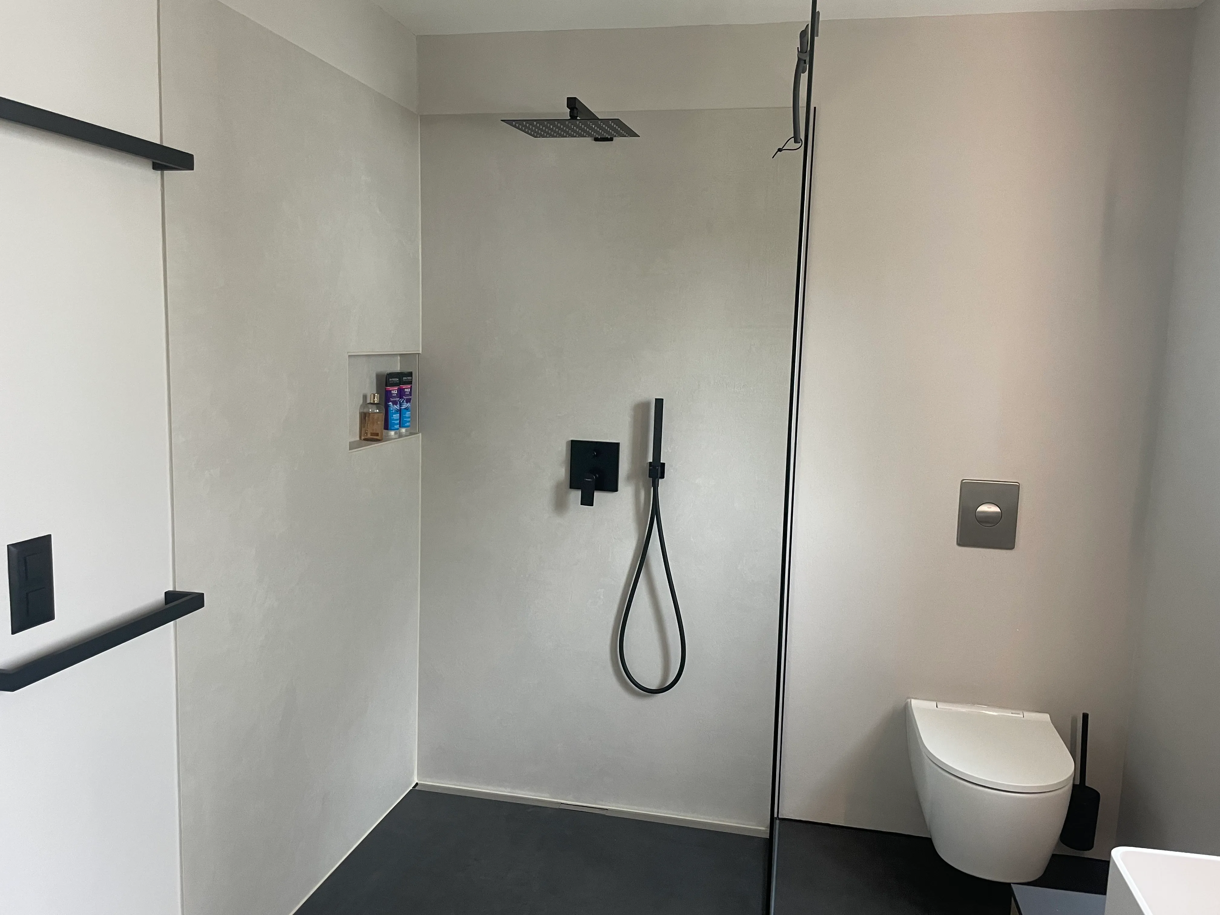 begehbare Dusche mit schwarzen Amatouren und Toilette
