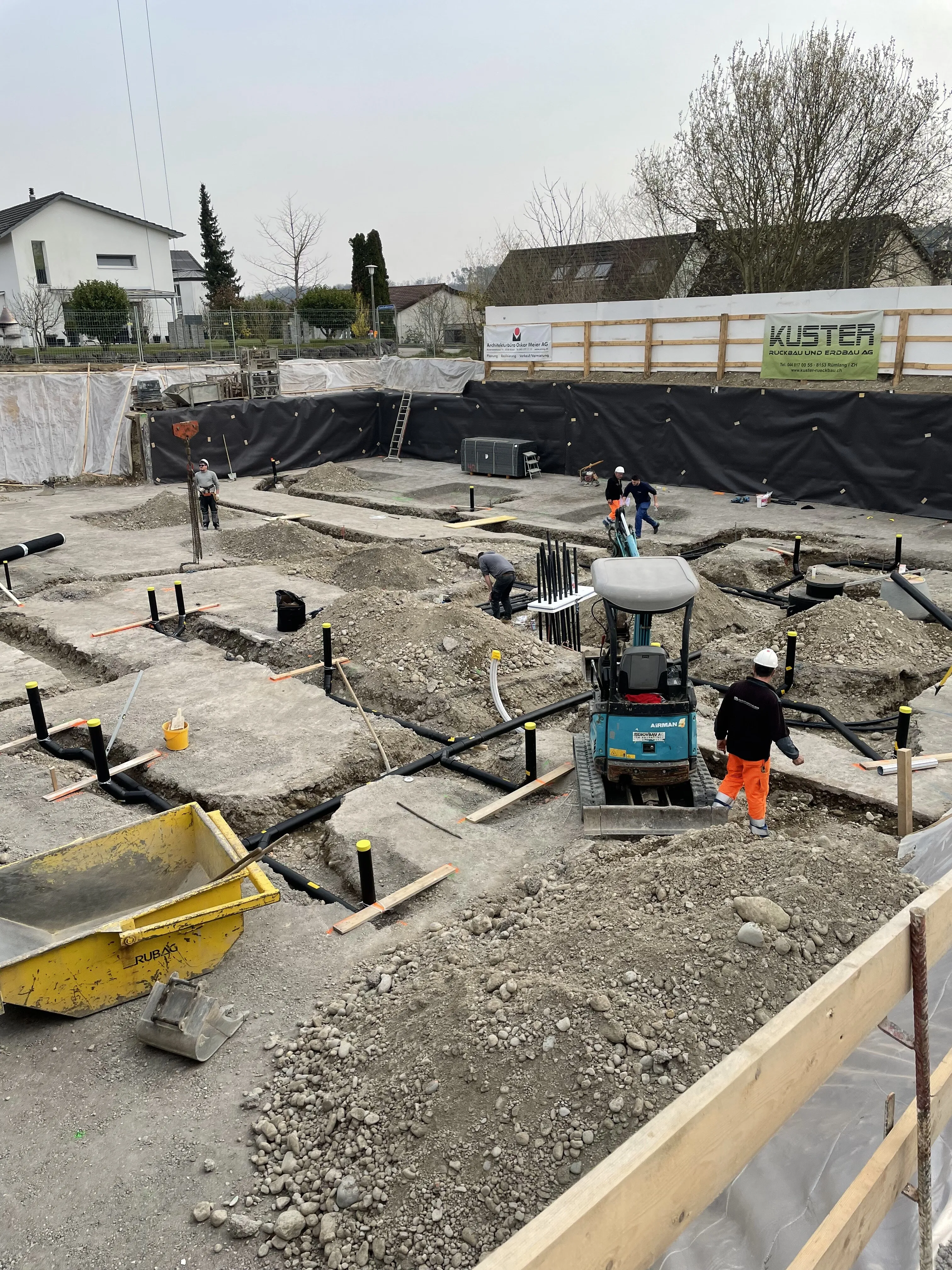 Baustelle mit schwarzen Rohren und Bauarbeiter