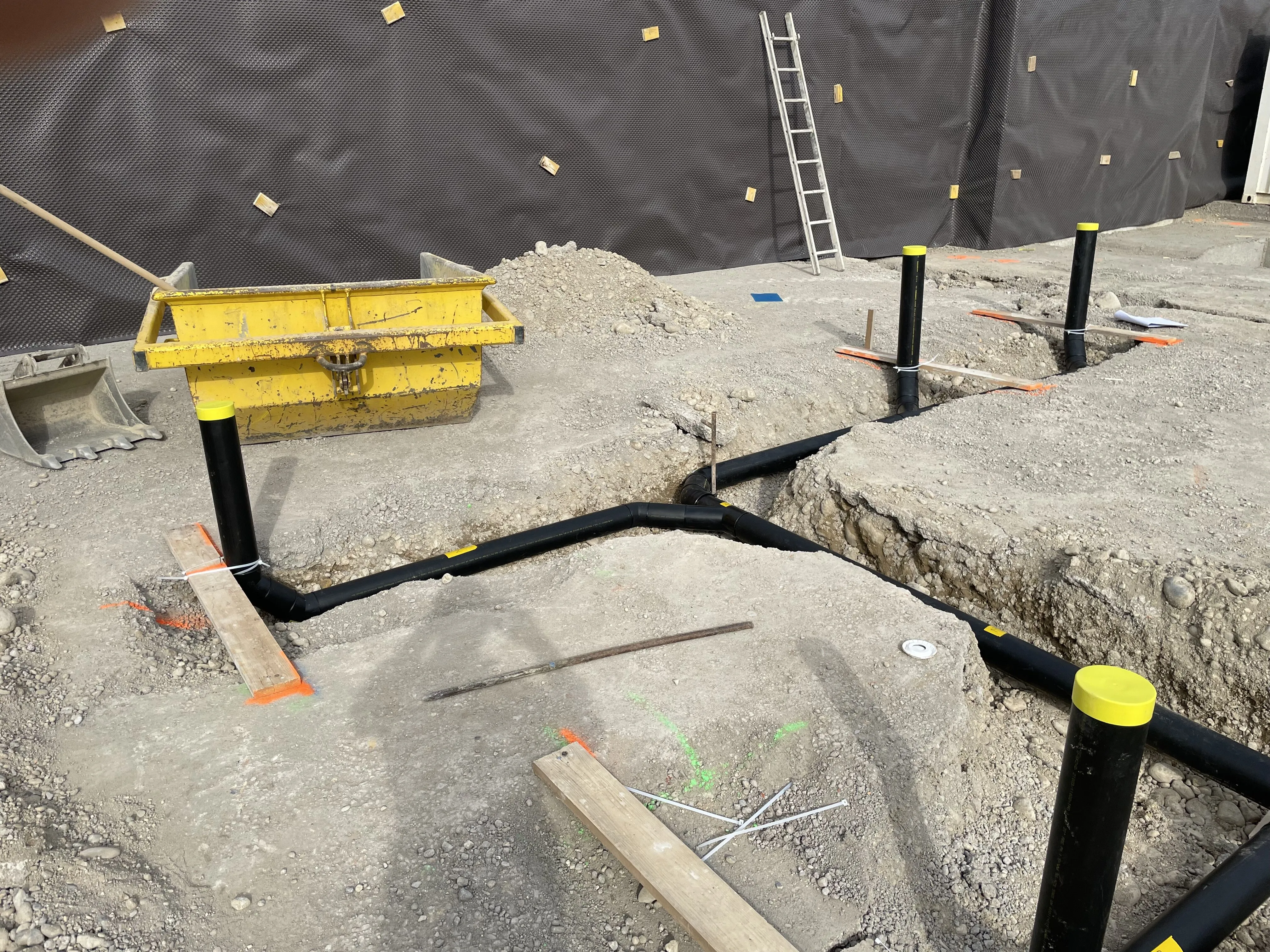Baustelle mit schwarzen Rohren und Bauarbeiter