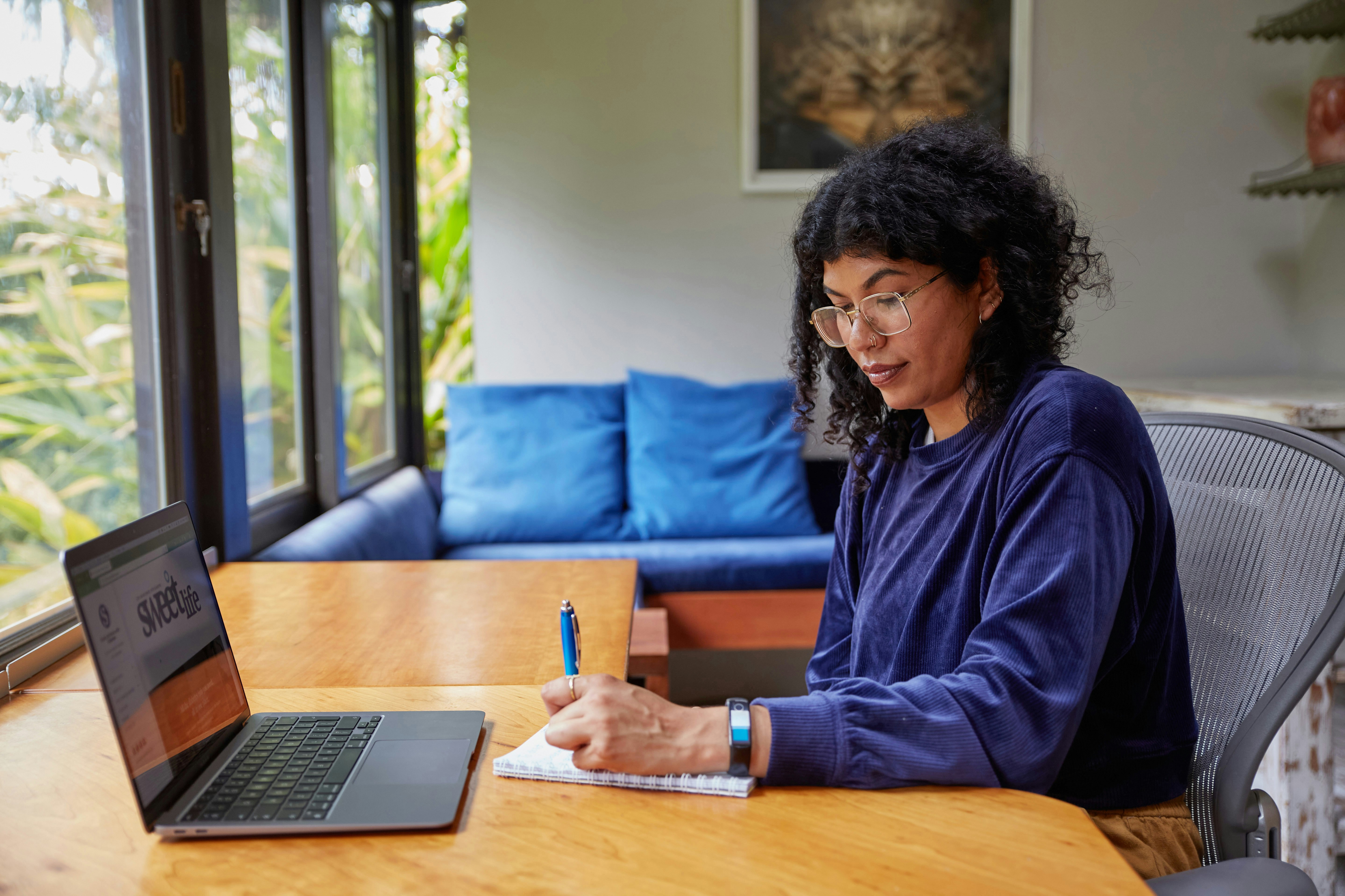 woman writing on notepad with laptop infront - Create Online Assessments
