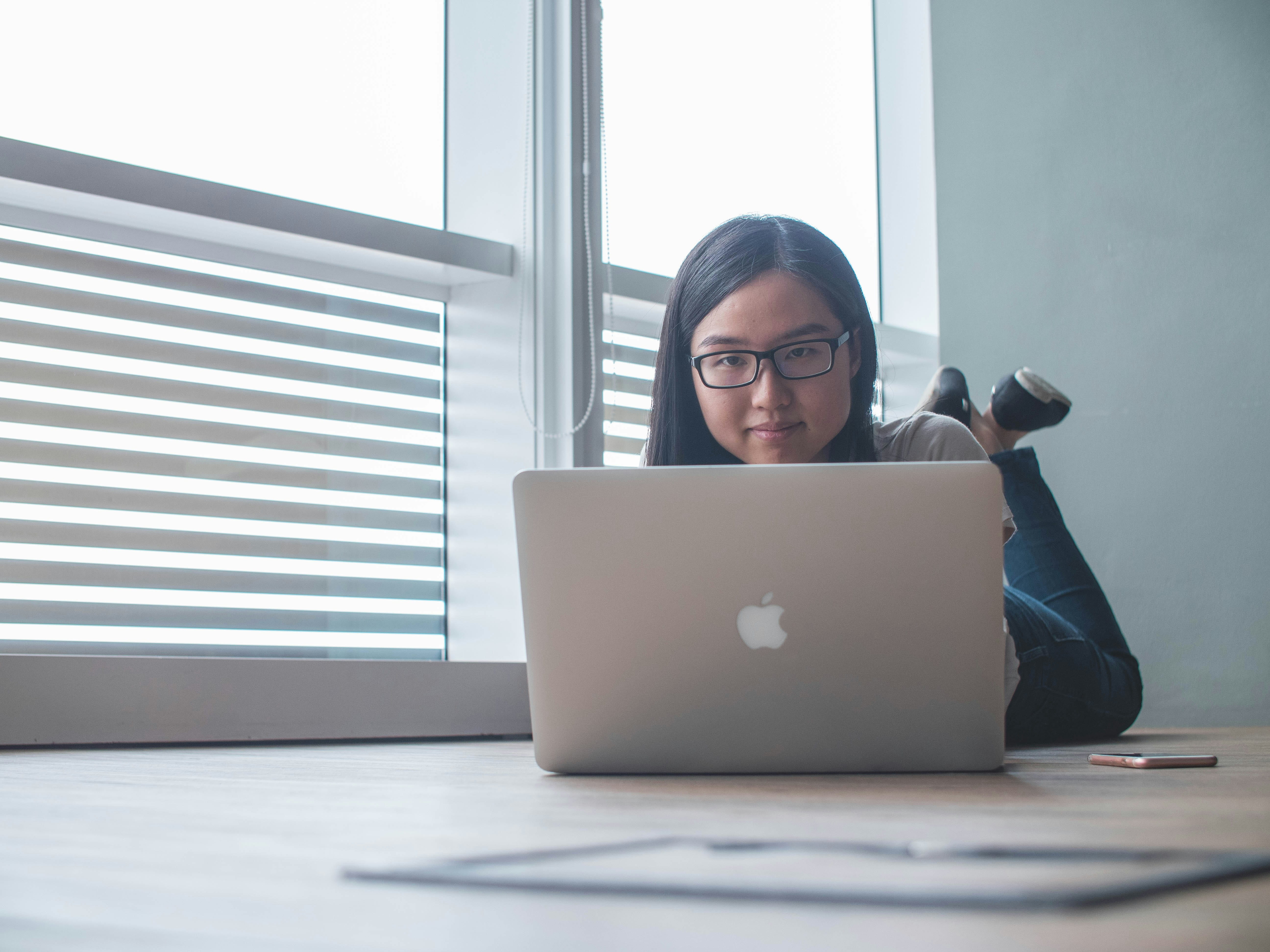 girl lying on floor and working on laptop -  Formative Assessment Using Technology