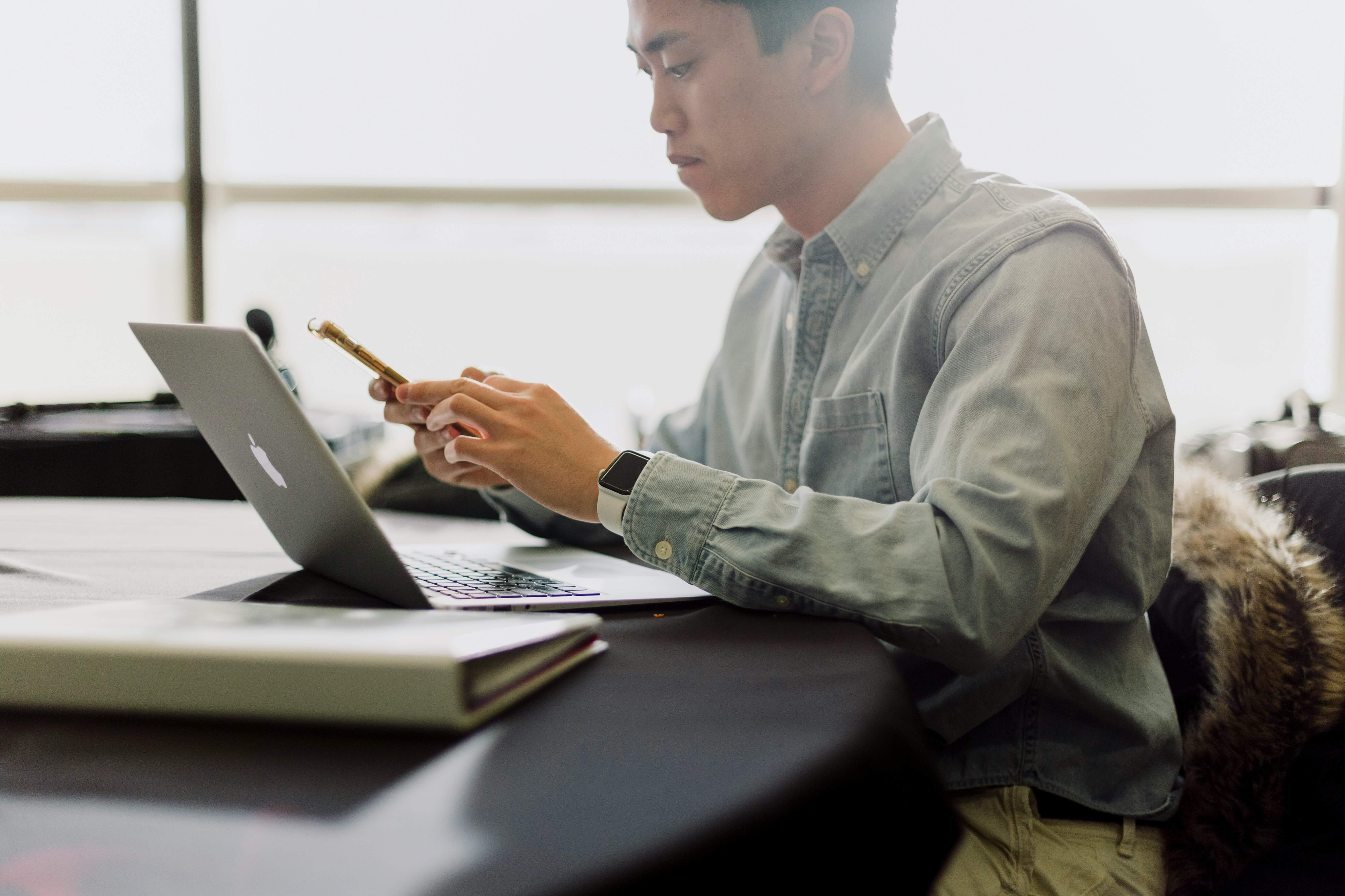 man working on a laptop and using mobile - Student Feedback Software