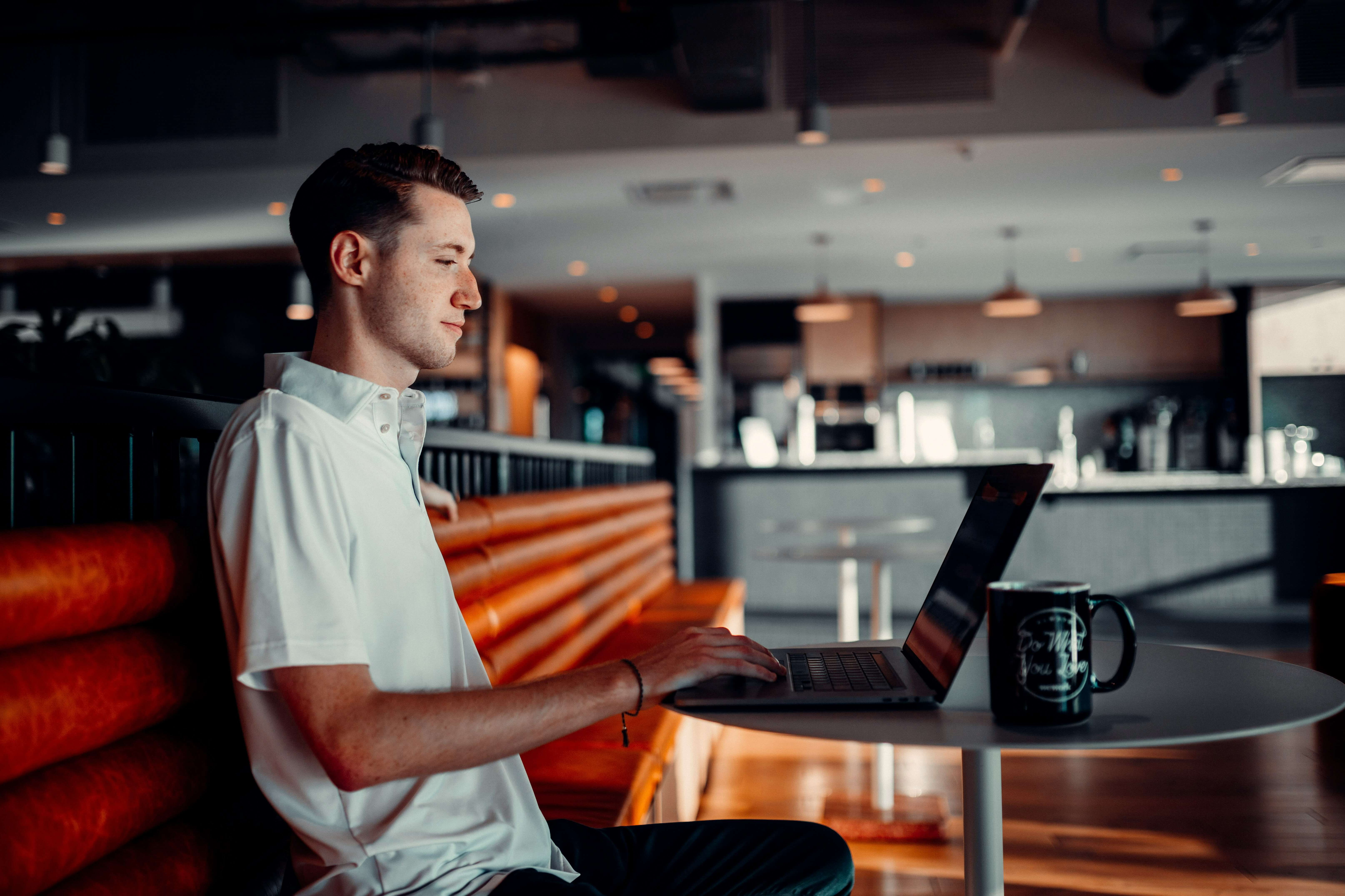 man working on laptop in cafeteria - AI Assessment Tools