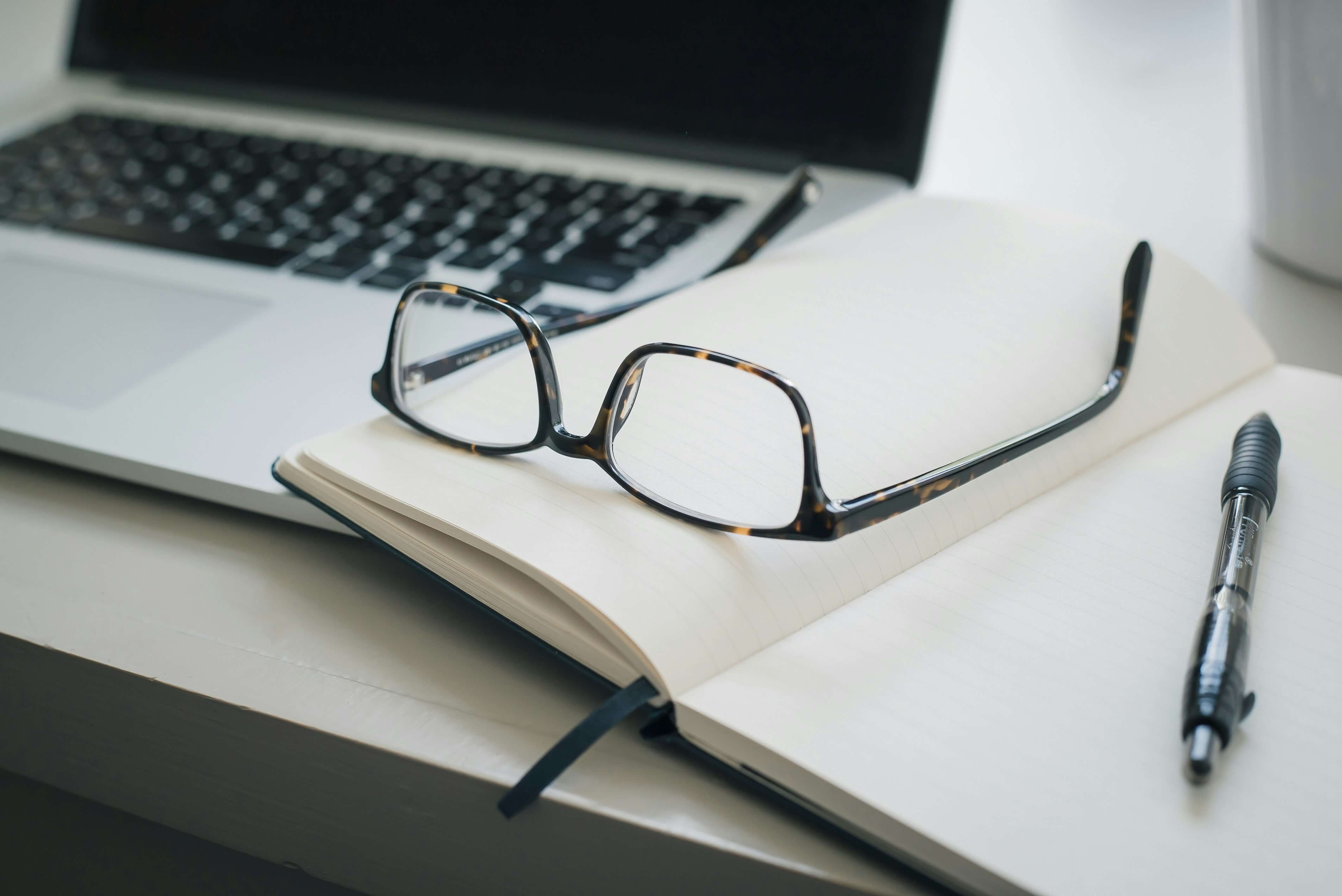 blank notebook with glasses on it - Essay Grading Rubric