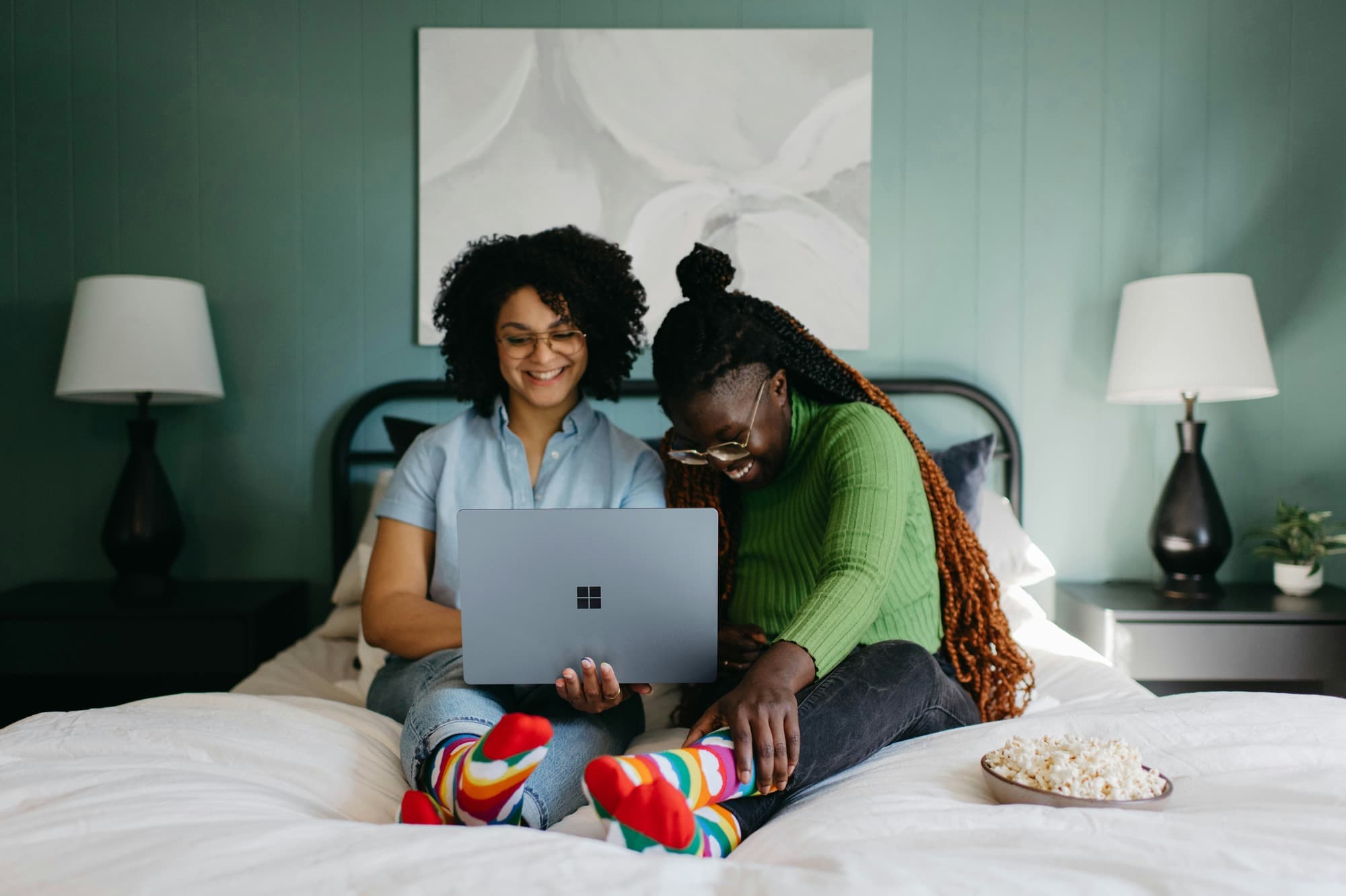 two women sitting on a bed and working on a laptop - Formative vs Summative Assessment