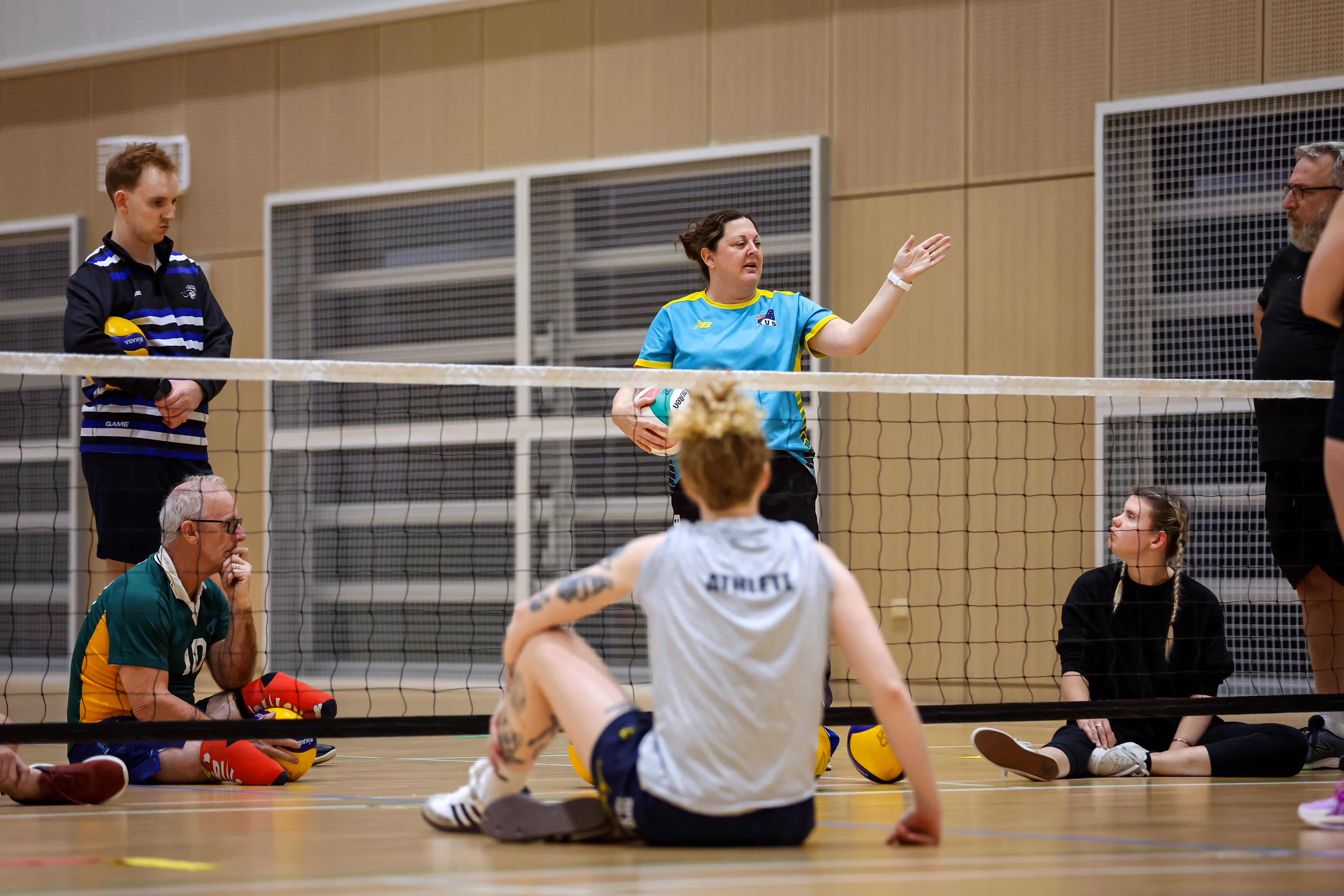Volleyball players in black Brisbane Bears uniforms celebrating together on court with crowd watching.