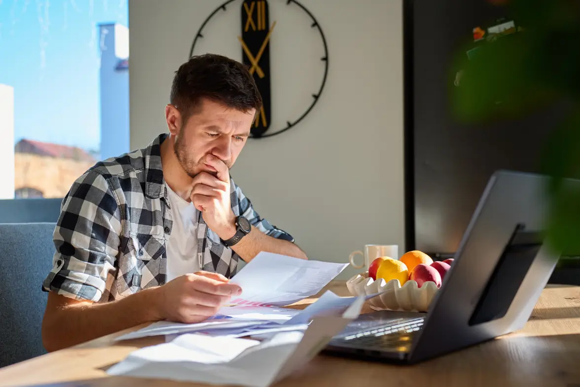 Person carefully reviewing coaching certification program documents and costs before making a decision