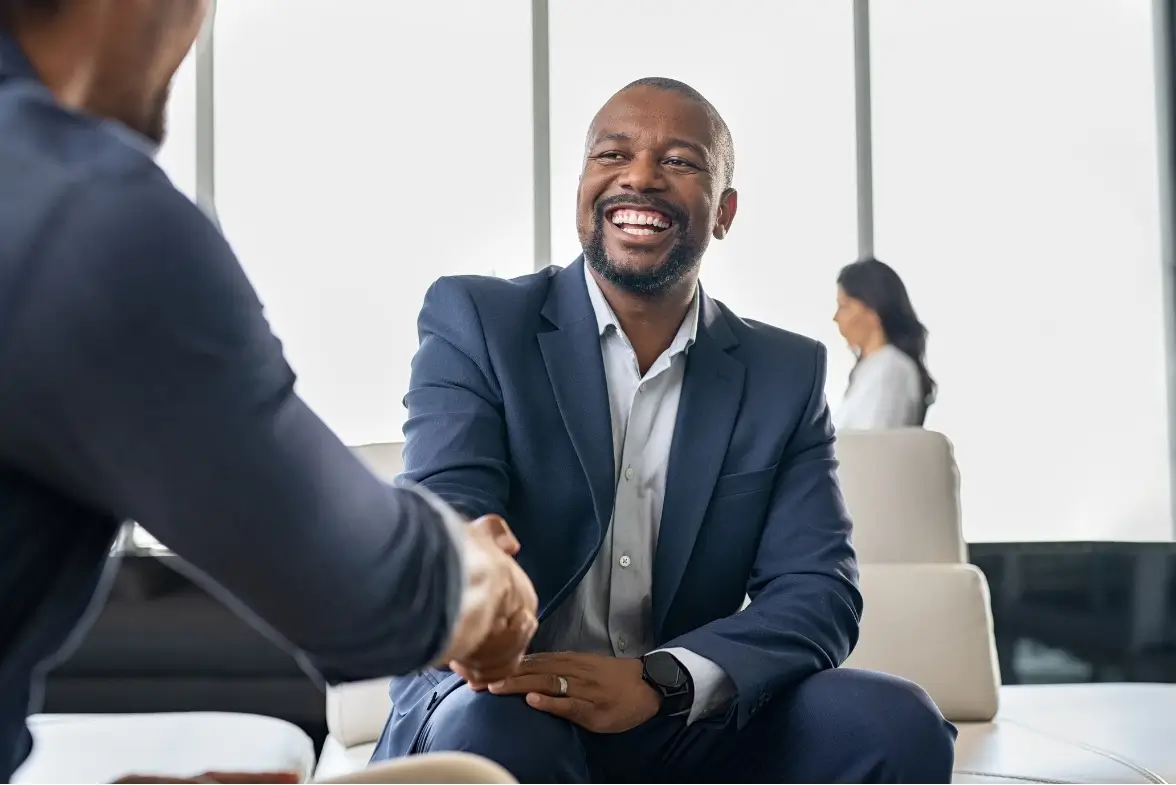 Two professionals shaking hands at the start of a coaching or mentoring relationship in a modern office setting