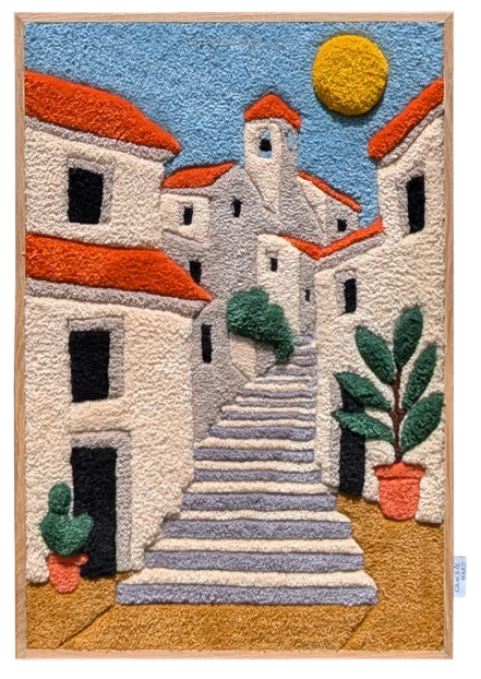 A textile artwork depicting a flamenco dancer in a vibrant red dress, captured mid-performance with one arm raised and the other holding a fan. The background features a textured blue sky and a pebble-strewn ground. The piece is displayed outdoors on a wooden easel, set against a brick facade with white-framed glass doors and black shutters