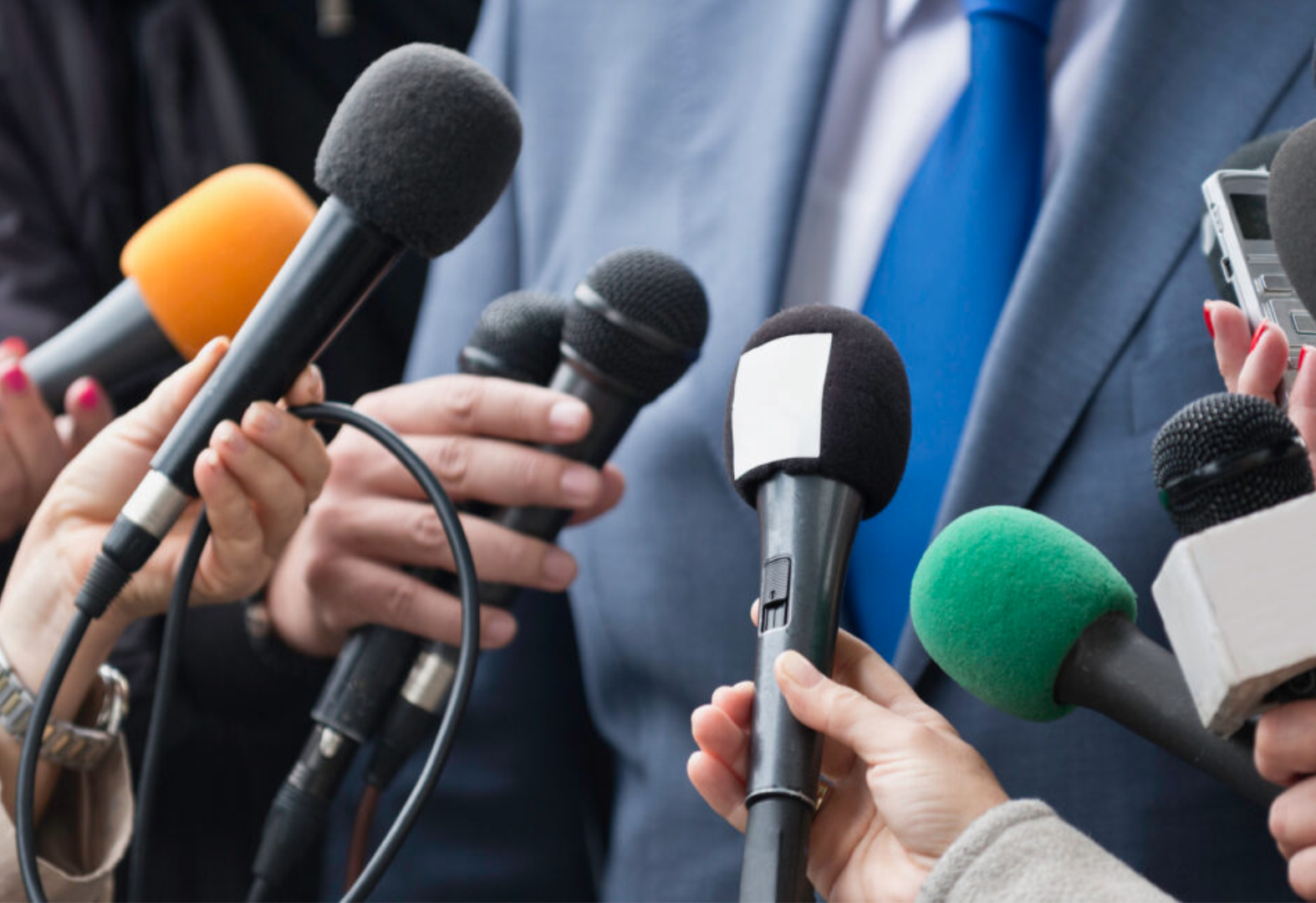 Man getting quizzed by reporters with microphones