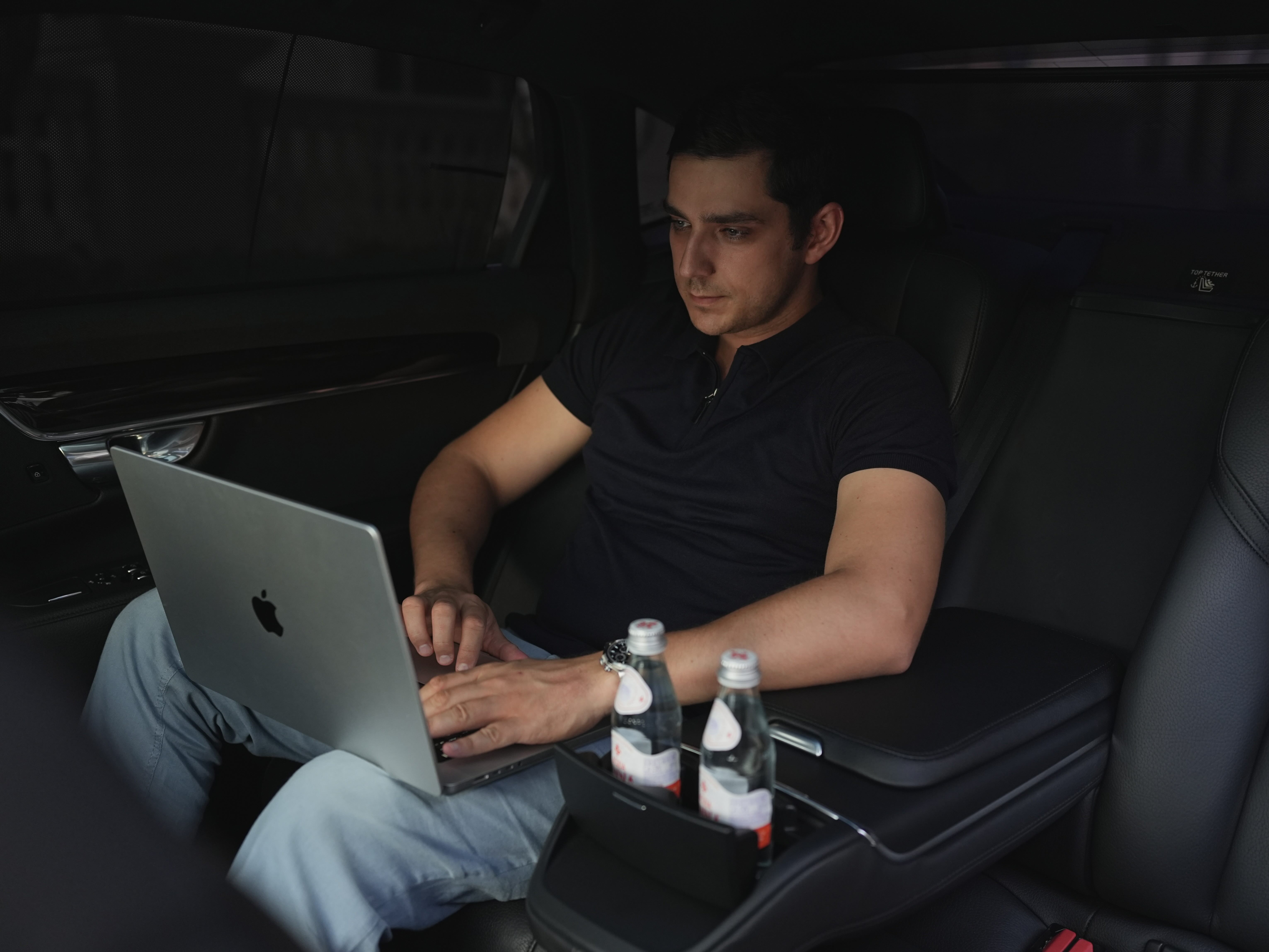 Executive client working on a laptop while riding in a luxury black SUV with captain seats, premium interior, and complimentary bottled water from Miami Choice Limo.