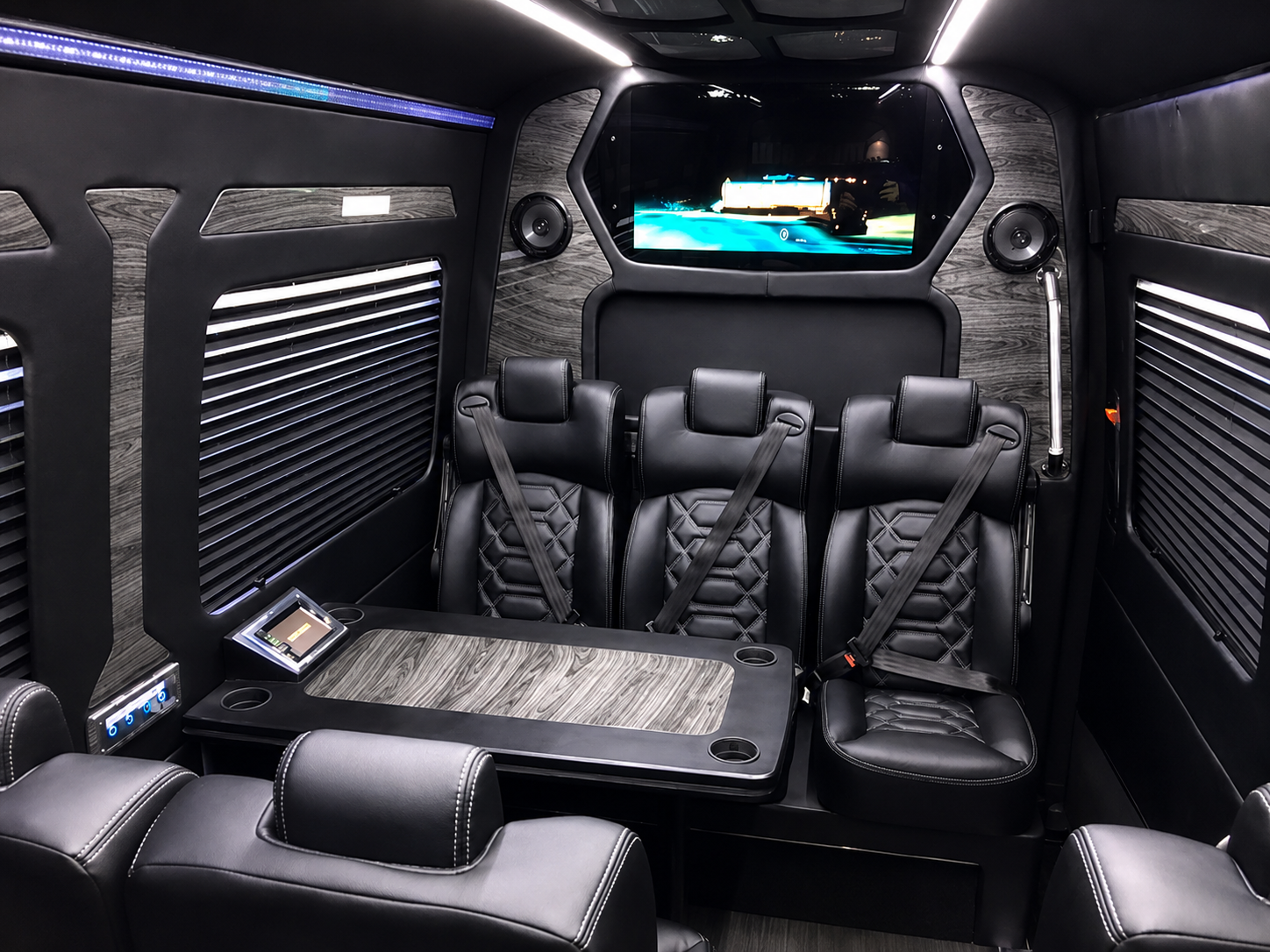 Miami Choice Limo luxury Mercedes-Benz Sprinter interior featuring premium black leather seating, wood-grain finishes, ambient lighting, entertainment screen, and executive passenger amenities.