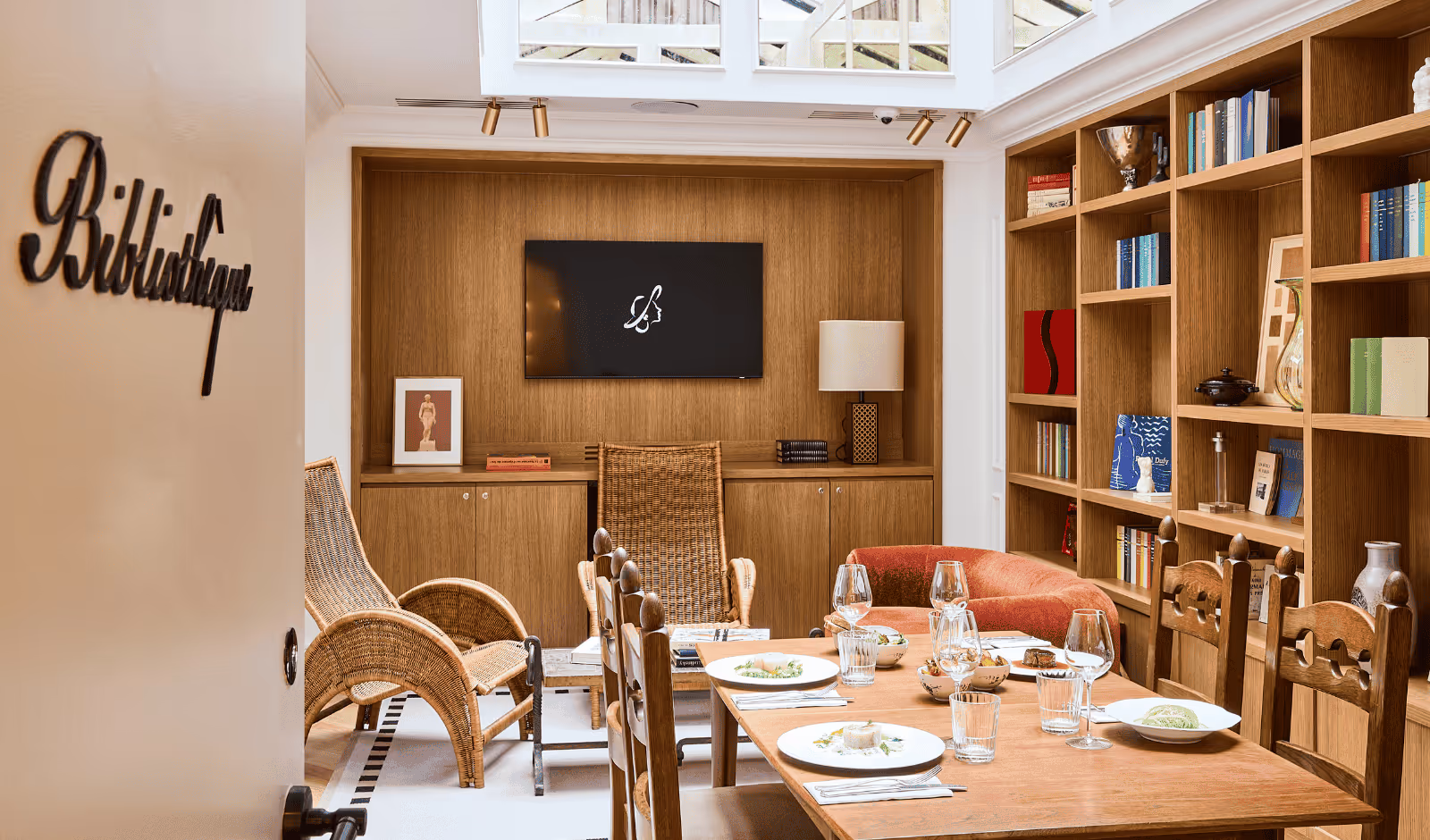 Bibliothèque élégante avec étagères remplies de livres et coin lecture confortable - Hôtel Noucha