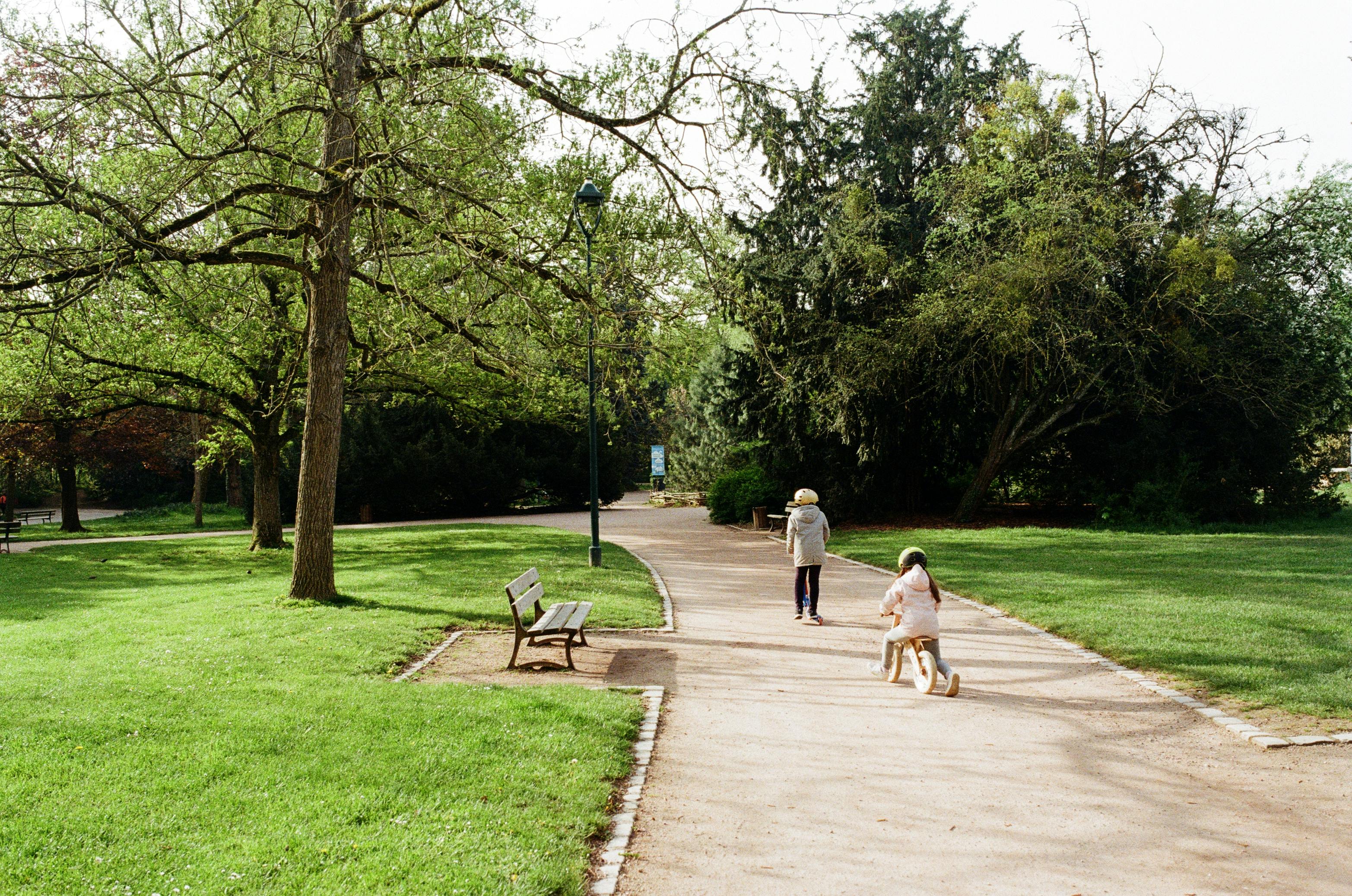 Parc parisien avec un enfant à vélo dans un cadre verdoyant.