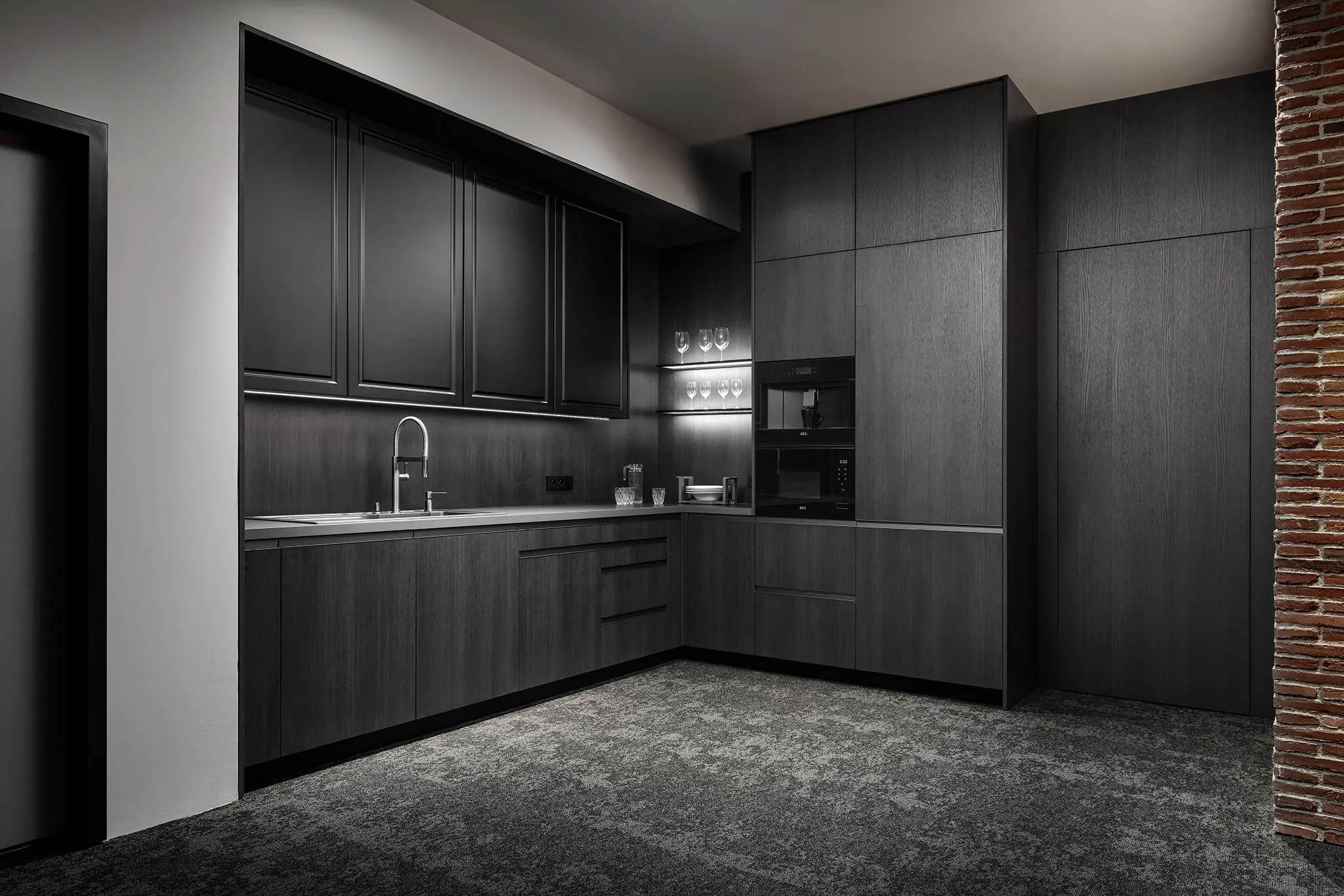 Minimalistická černá kuchyně s šedými bezúchytkovými dvířky a integrovanými spotřebiči