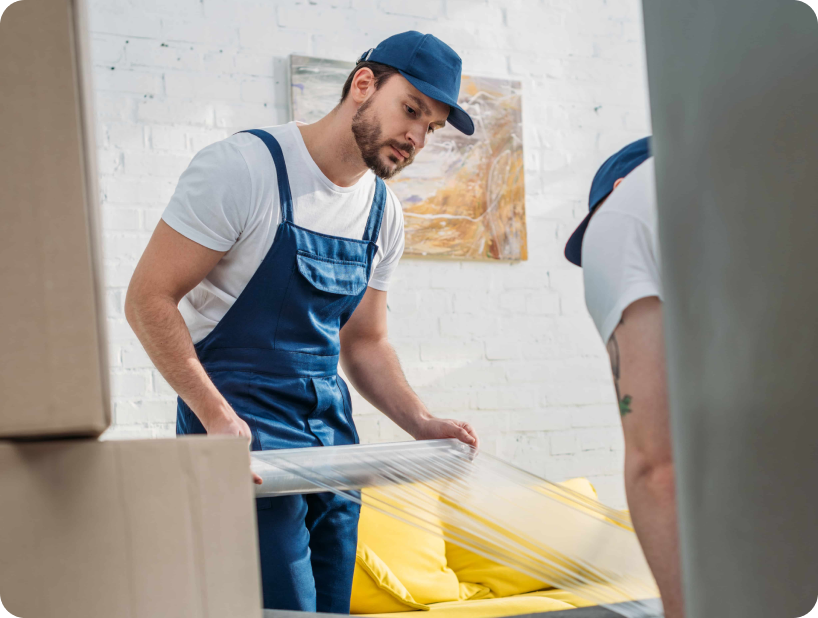Une jeune fille aux cheveux bouclés souriant en préparant une pile de livres dans une boîte, mettant en valeur l'organisation et la préparation essentielles pour un déménagement réussi.