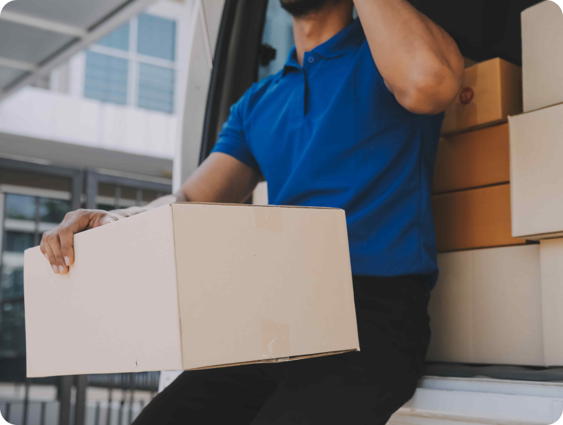 Deux déménageurs en combinaison bleue et casquette blanche chargeant soigneusement des cartons étiquetés "Fragile" dans une camionnette.