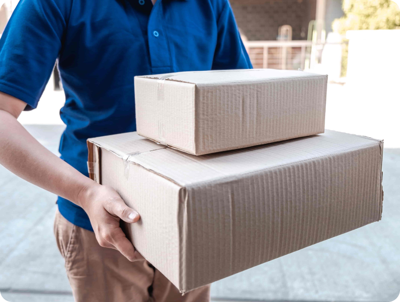 Un déménageur professionnel en uniforme orange soulevant un grand carton depuis un camion lors d’un déménagement d’objets lourds par une journée ensoleillée.
