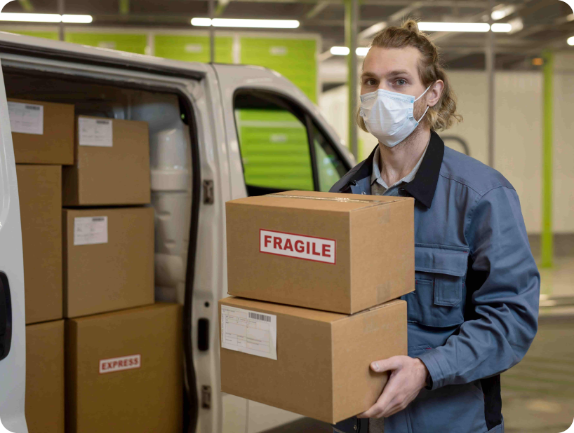 Deux déménageurs en combinaison bleue et casquette blanche chargeant soigneusement des cartons étiquetés "Fragile" dans une camionnette.