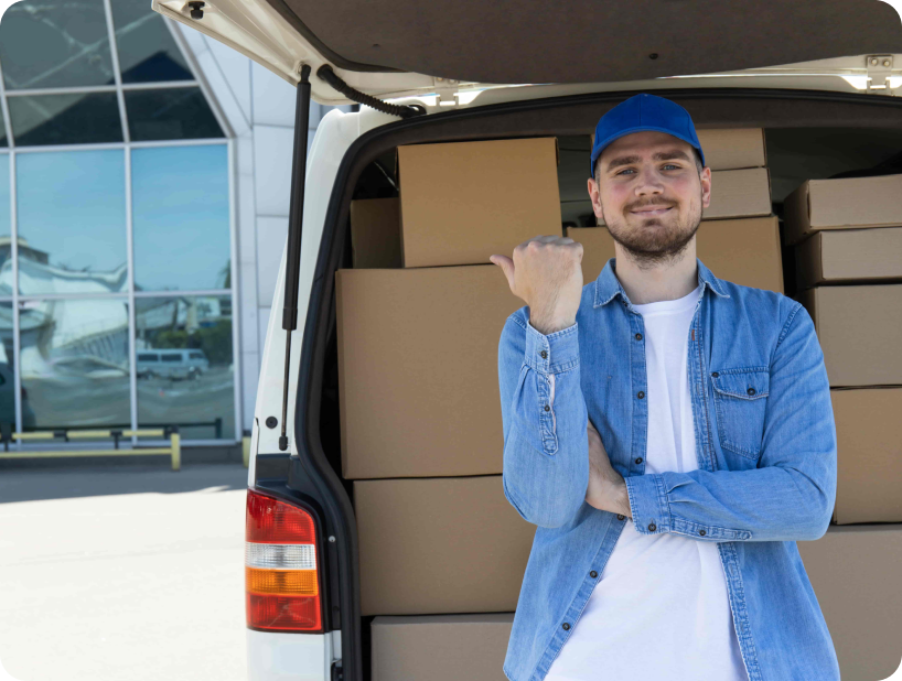 Deux déménageurs en combinaison bleue et casquette blanche chargeant soigneusement des cartons étiquetés "Fragile" dans une camionnette.