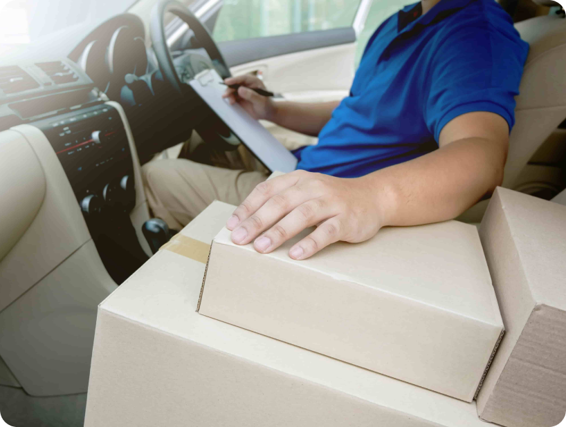 Un déménageur professionnel en uniforme orange soulevant un grand carton depuis un camion lors d’un déménagement d’objets lourds par une journée ensoleillée.