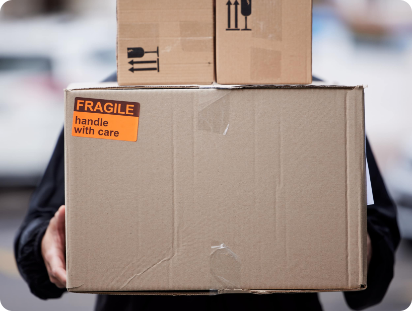 Two movers in blue overalls and white caps carefully loading boxes labeled "Fragile" into a van.
