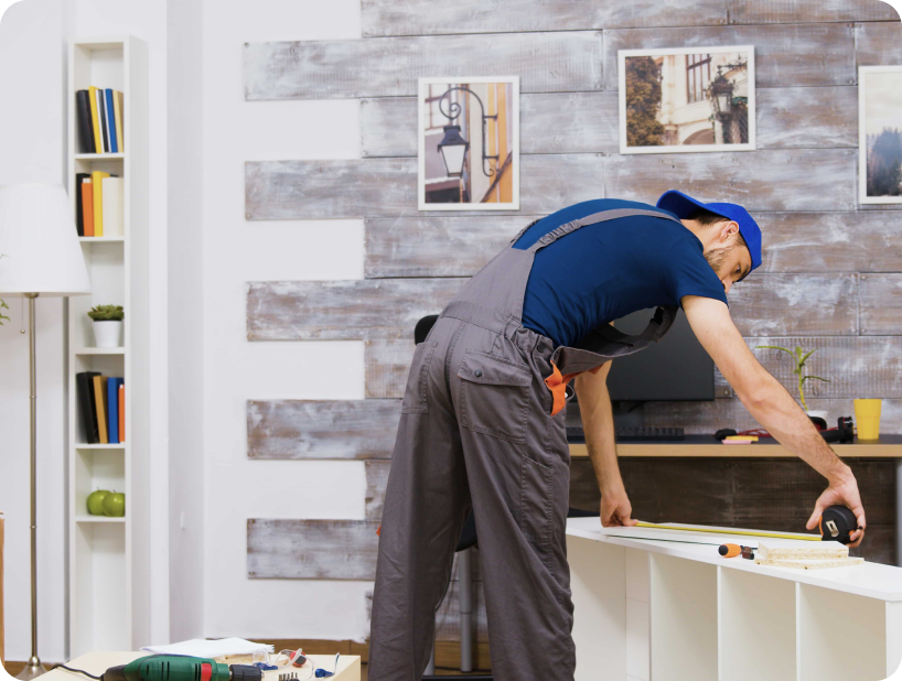 Un déménageur professionnel en uniforme orange soulevant un grand carton depuis un camion lors d’un déménagement d’objets lourds par une journée ensoleillée.
