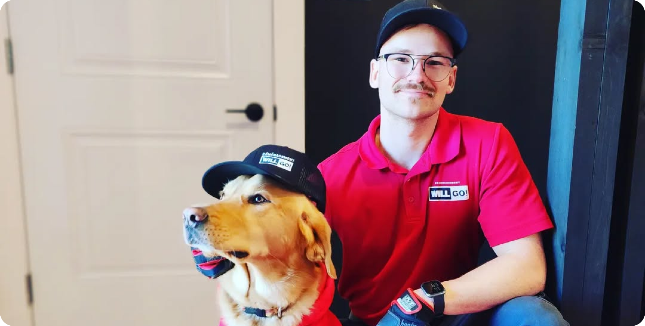 Un déménageur en hoodie rouge Déménagement WillGo serrant la main d’un propriétaire devant une maison en brique moderne.
