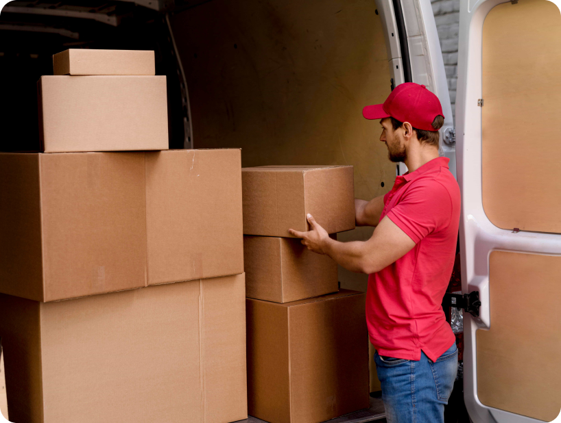 Un déménageur en hoodie rouge Déménagement WillGo déchargeant du matériel d’un camion près d’un immeuble résidentiel.