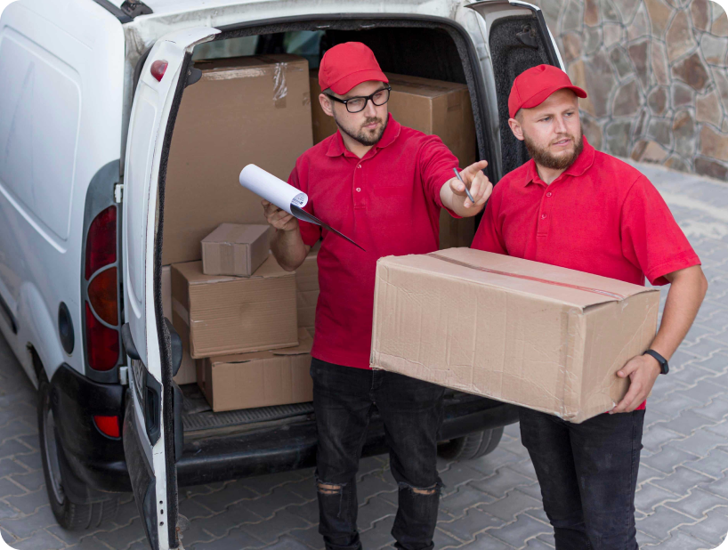 Deux déménageurs en combinaison bleue et casquette blanche chargeant soigneusement des cartons étiquetés "Fragile" dans une camionnette.