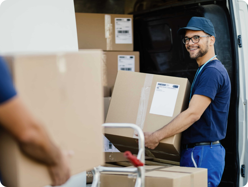 Un déménageur en hoodie rouge Déménagement WillGo déchargeant du matériel d’un camion près d’un immeuble résidentiel.