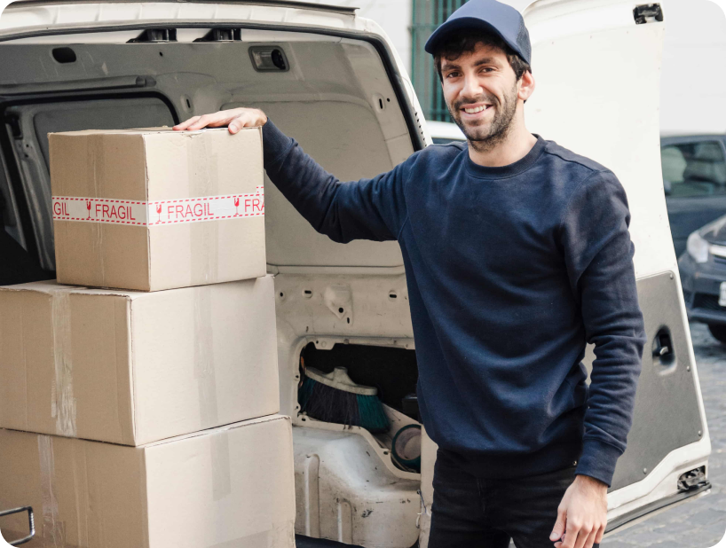 Deux déménageurs en combinaison bleue et casquette blanche chargeant soigneusement des cartons étiquetés "Fragile" dans une camionnette.
