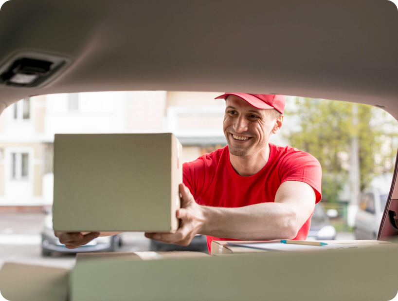 Un déménageur en hoodie rouge Déménagement WillGo déchargeant du matériel d’un camion près d’un immeuble résidentiel.