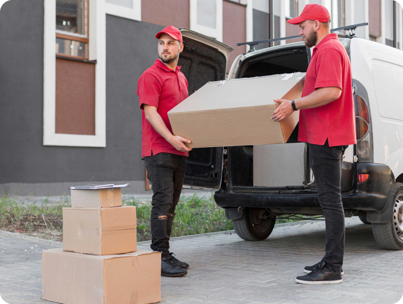 Deux déménageurs en combinaison bleue et casquette blanche chargeant soigneusement des cartons étiquetés "Fragile" dans une camionnette.