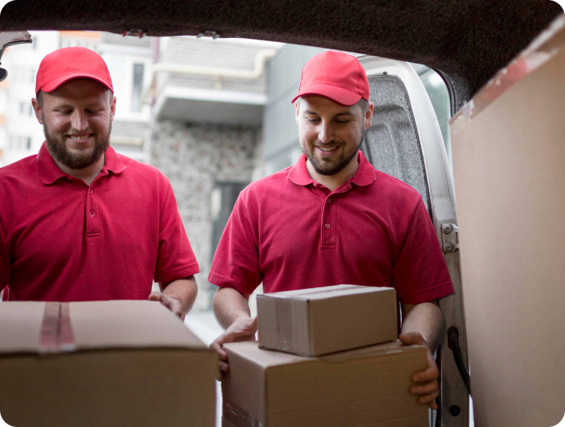 Un déménageur en hoodie rouge Déménagement WillGo déchargeant du matériel d’un camion près d’un immeuble résidentiel.