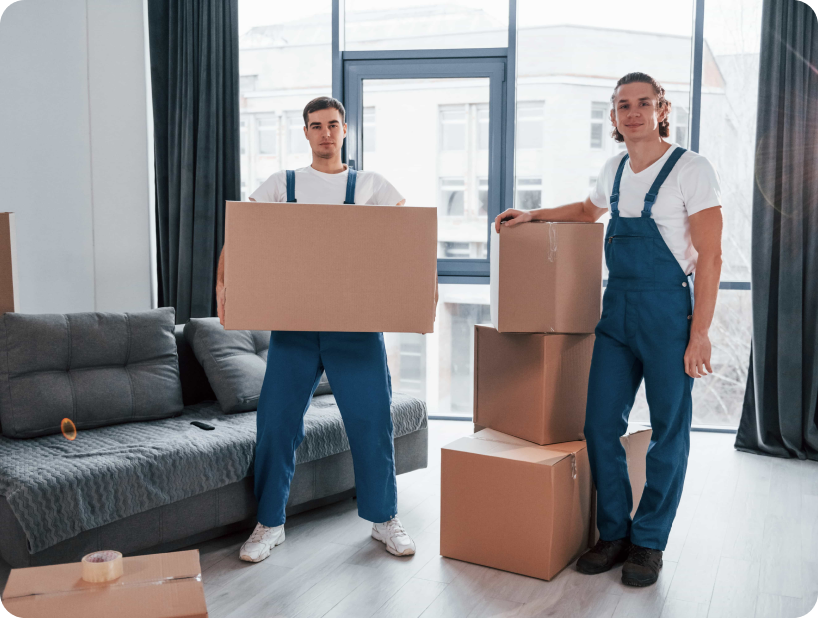 Deux déménageurs en combinaison bleue et casquette blanche chargeant soigneusement des cartons étiquetés "Fragile" dans une camionnette.