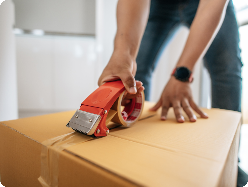 Deux déménageurs en combinaison bleue et casquette blanche chargeant soigneusement des cartons étiquetés "Fragile" dans une camionnette.