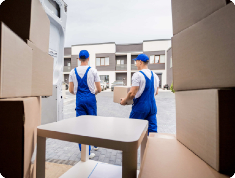 Deux déménageurs en combinaison bleue et casquette blanche chargeant soigneusement des cartons étiquetés "Fragile" dans une camionnette.