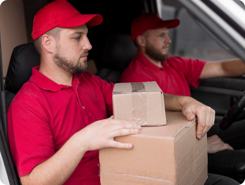 Deux déménageurs en combinaison bleue et casquette blanche chargeant soigneusement des cartons étiquetés "Fragile" dans une camionnette.