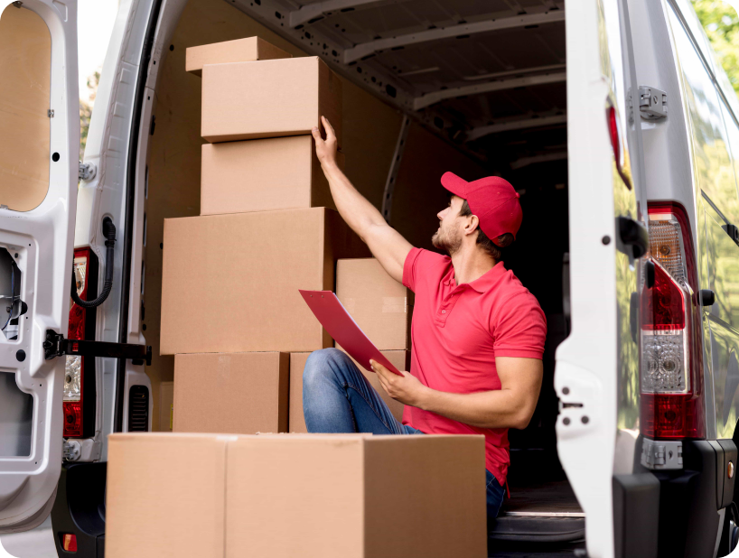 Deux déménageurs en combinaison bleue et casquette blanche chargeant soigneusement des cartons étiquetés "Fragile" dans une camionnette.